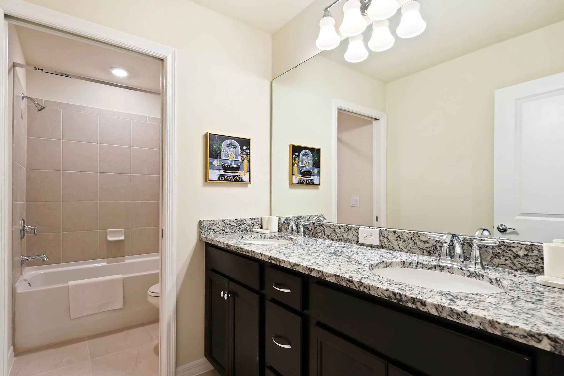 Elegant full bathroom featuring a dual-sink granite vanity and tiled tub/shower combo.