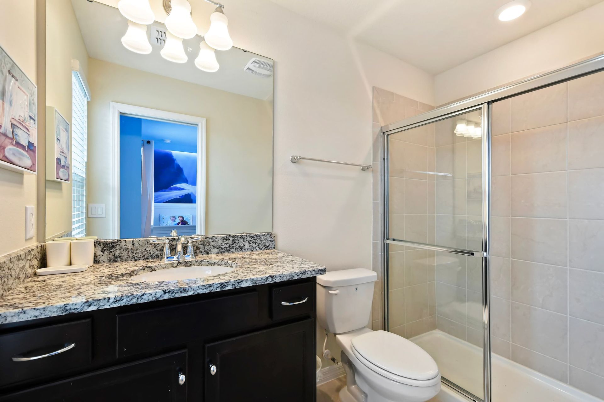 Frozen-themed ensuite with sleek granite vanity and spacious glass shower.