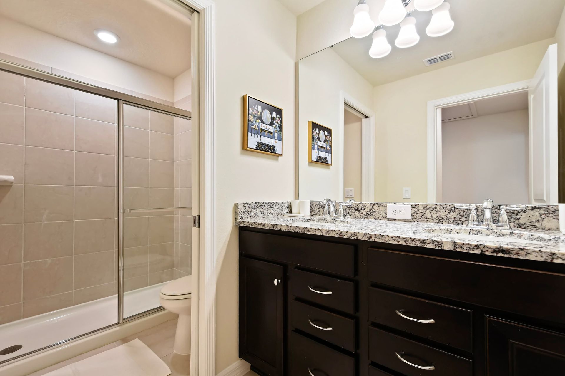 Sleek bathroom with granite double vanity and a spacious glass-enclosed shower.