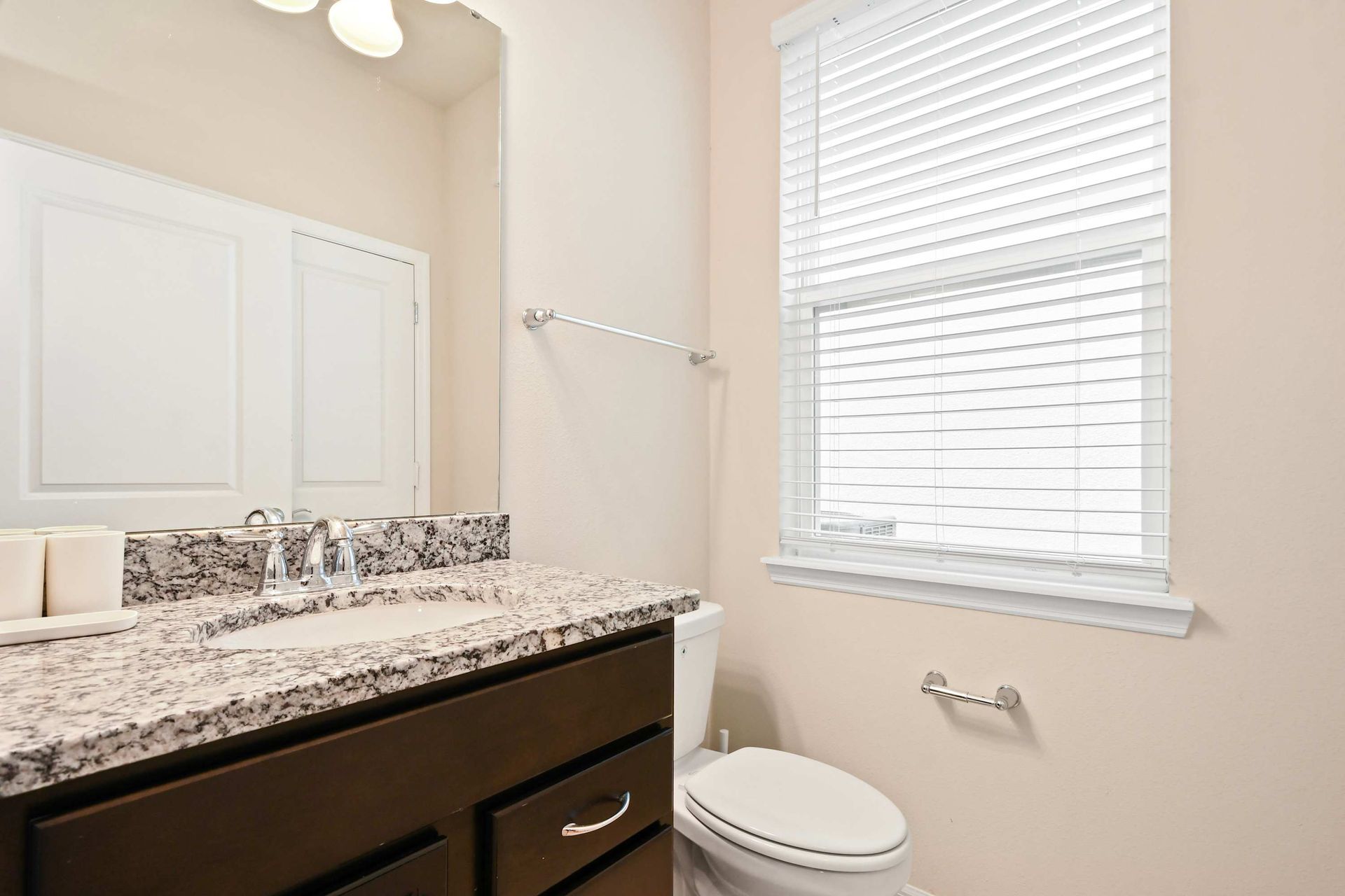 Bright and modern half bath with granite countertop and sleek dark cabinetry.