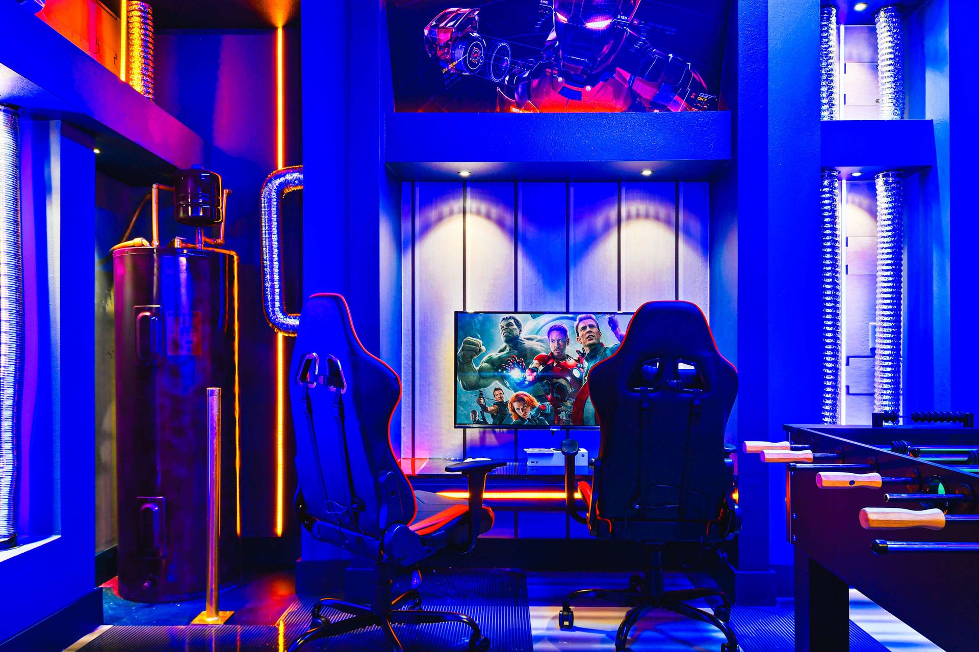 Epic superhero-themed gaming room with LED lighting, dual gaming chairs, and foosball.