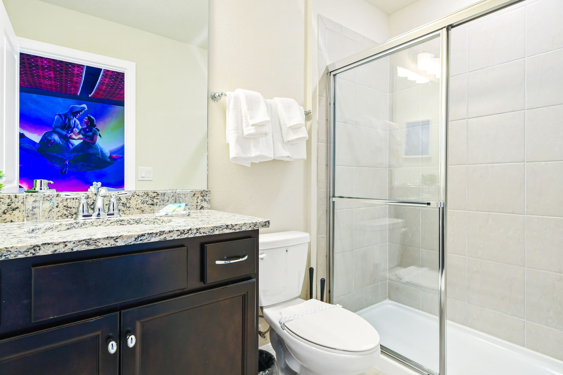 Bright bathroom with granite vanity, glass shower, and fun Minion-themed decor
