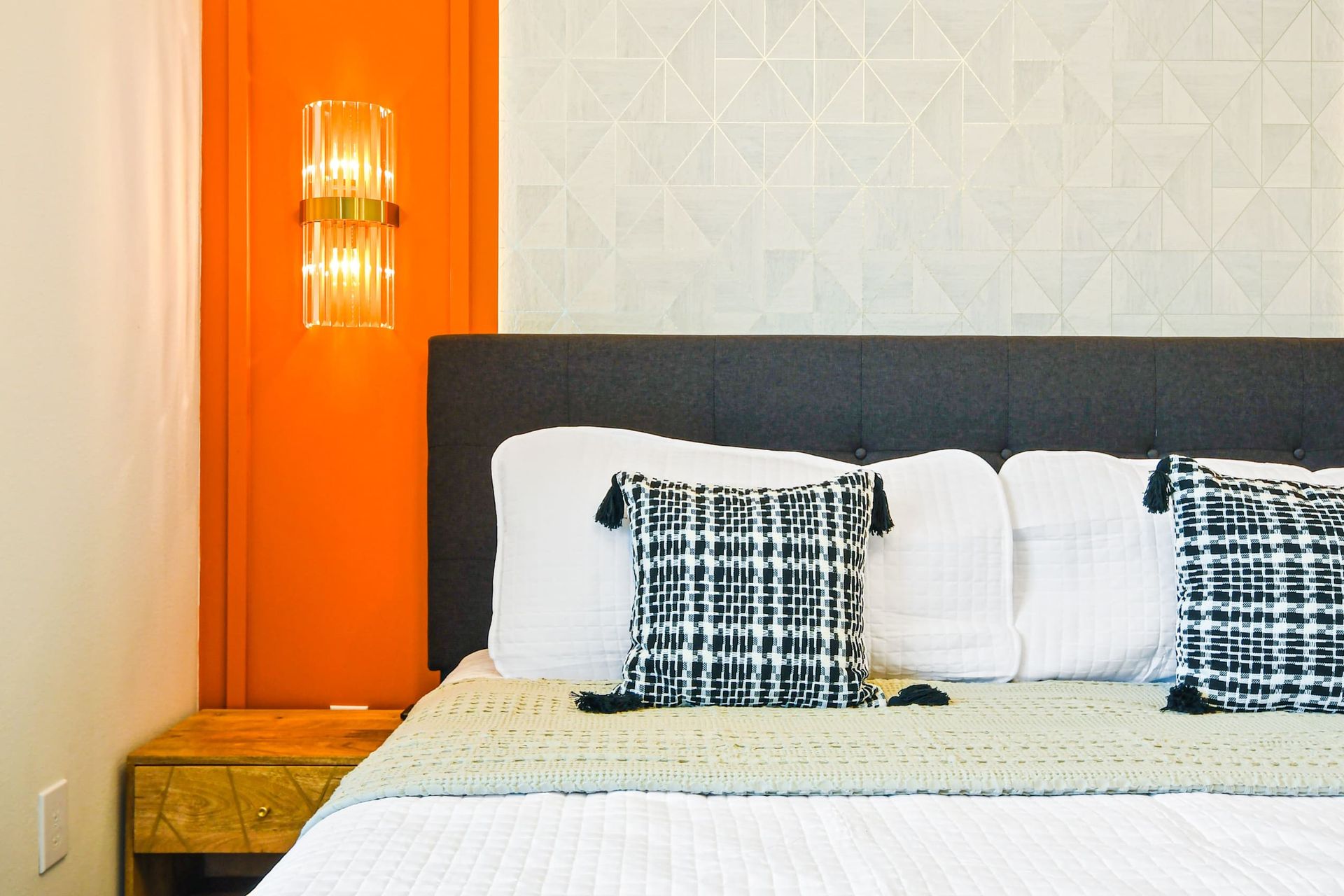 Modern cozy bedroom with bold orange accents, plush bedding, and stylish lighting
