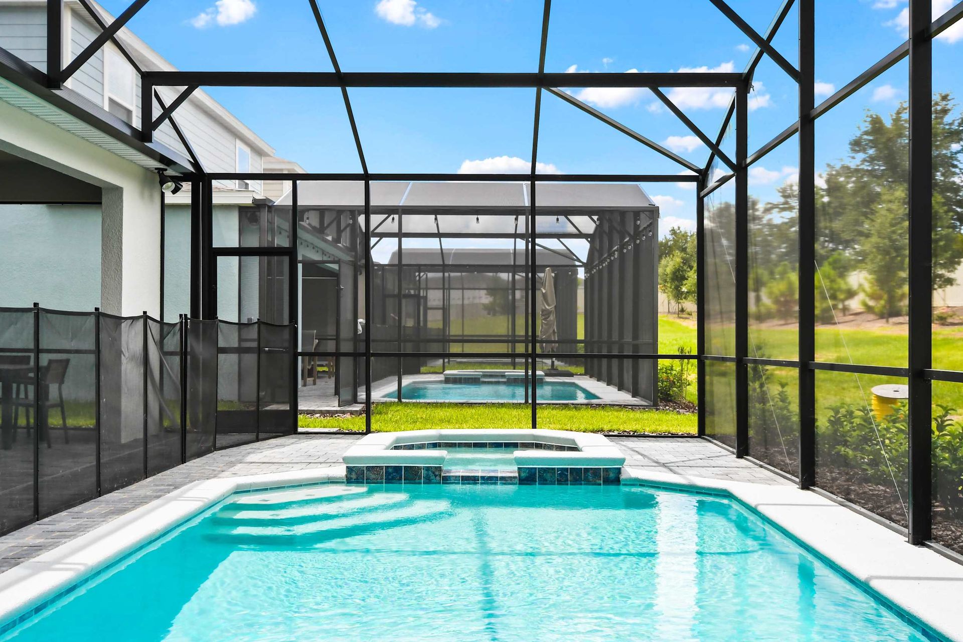 Sunny screened pool and spa with patio seating, perfect for relaxing family fun
