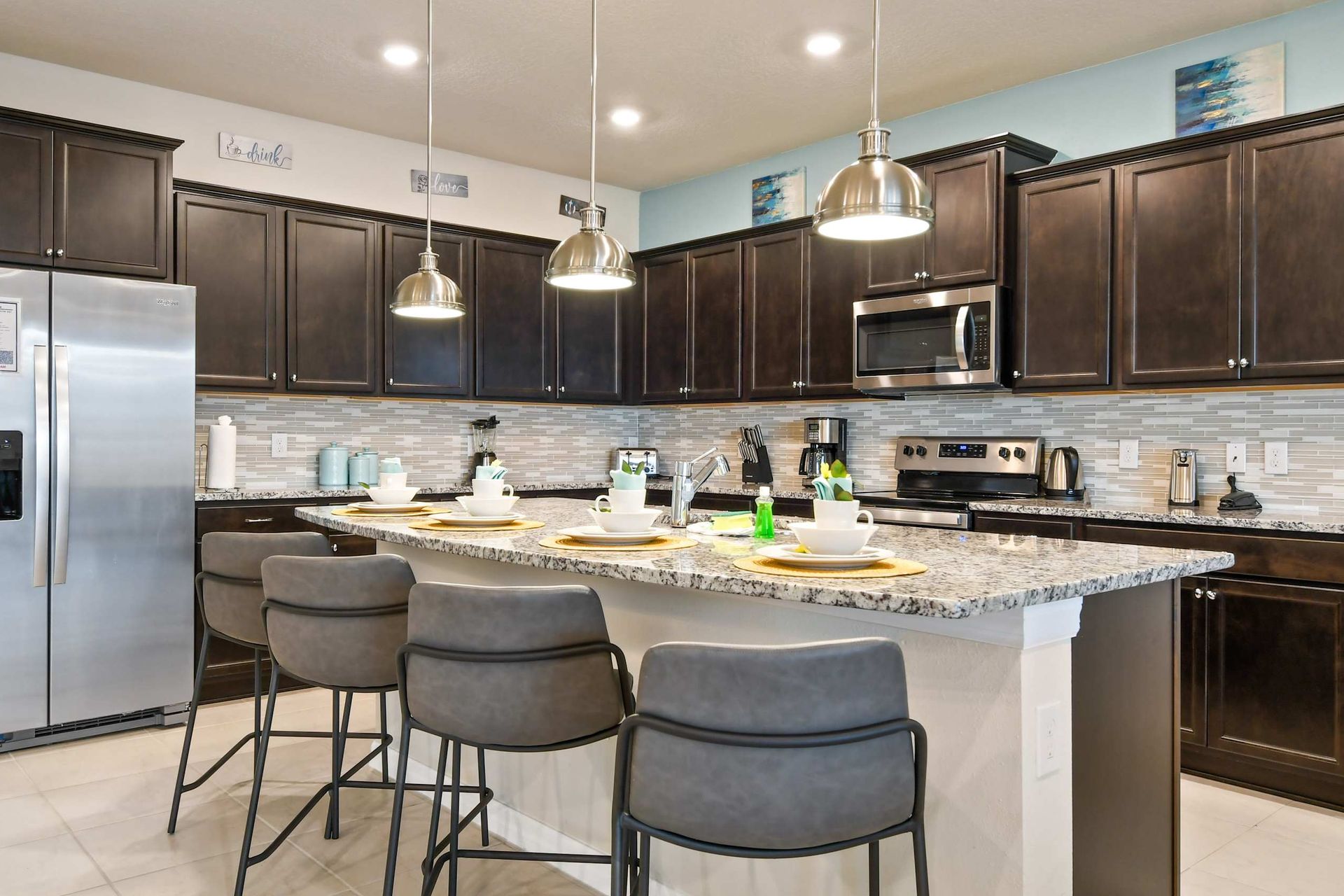 Modern kitchen with granite countertops, dark cabinets, and a spacious island.