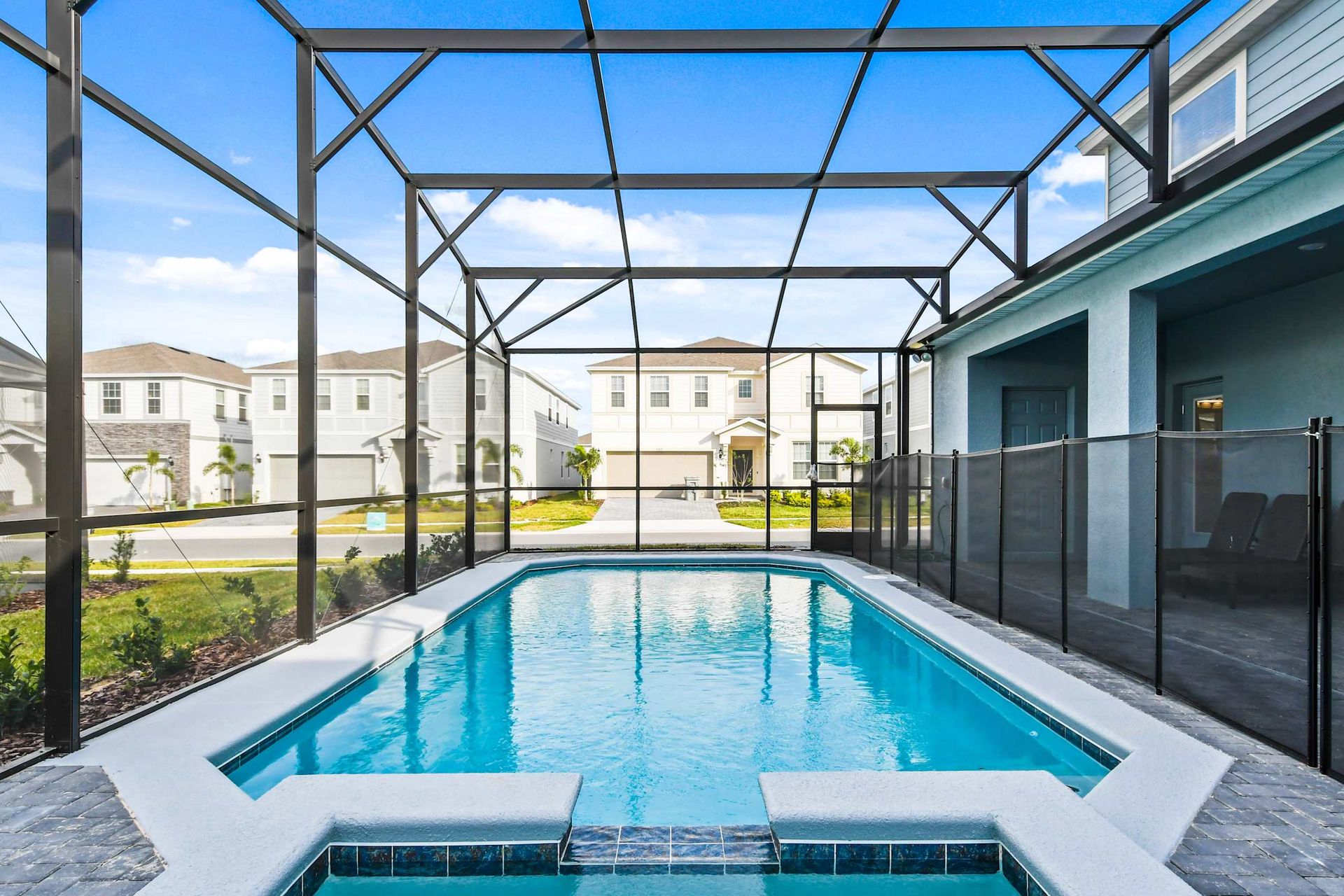 Private screened-in pool with sunny patio, lounge chairs, and modern safety fencing.