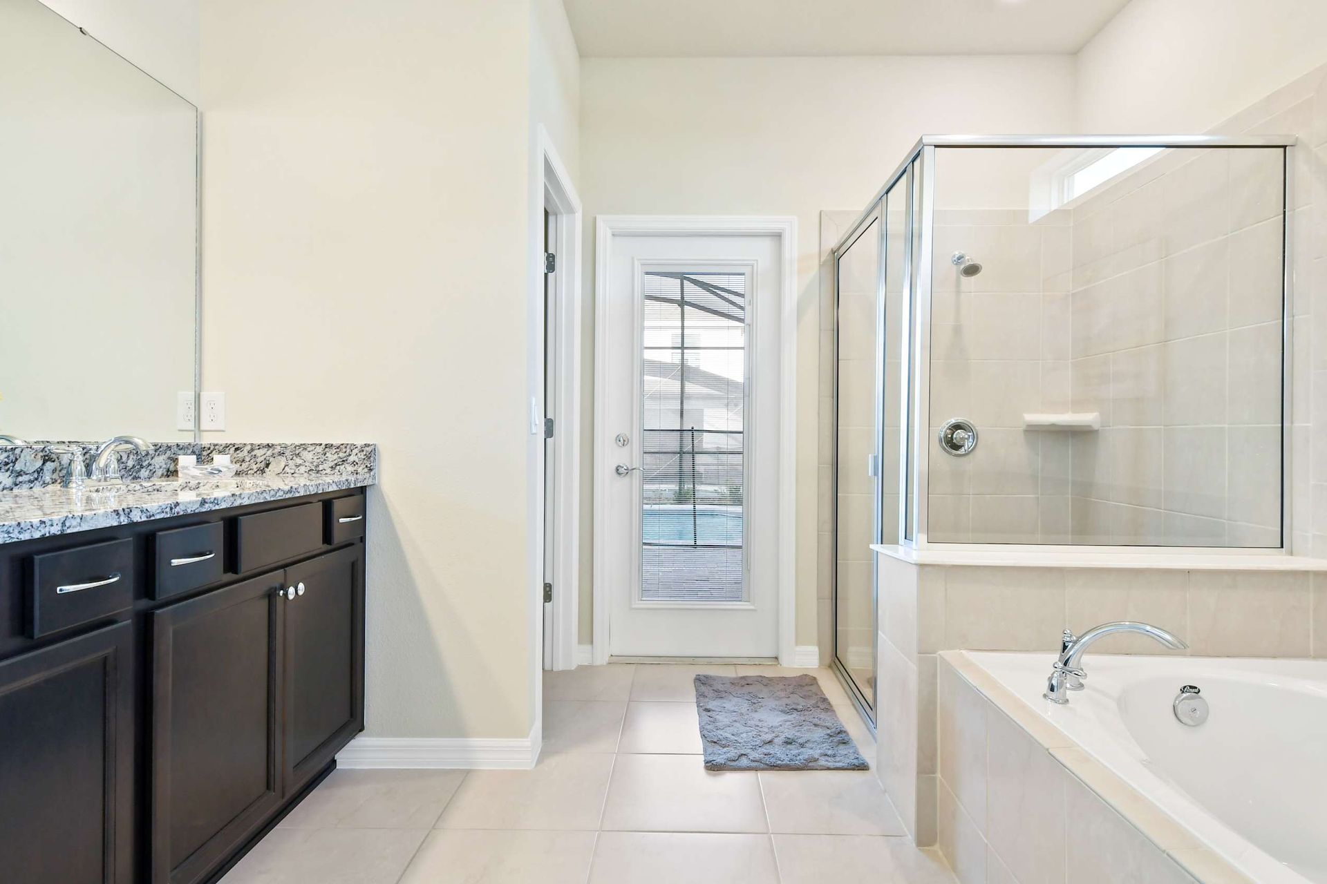 Spacious spa-style bathroom with soaking tub, walk-in shower, and pool access.