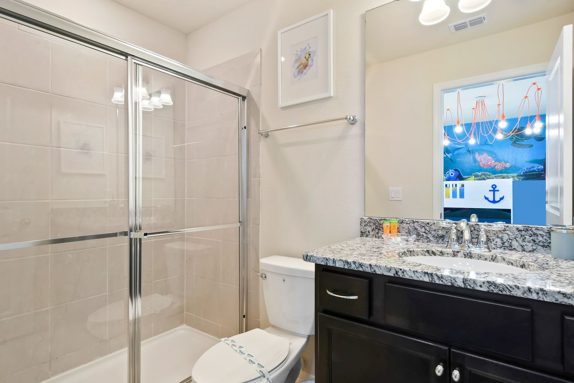 Modern bathroom with granite vanity, glass shower, and fun ocean-themed view.