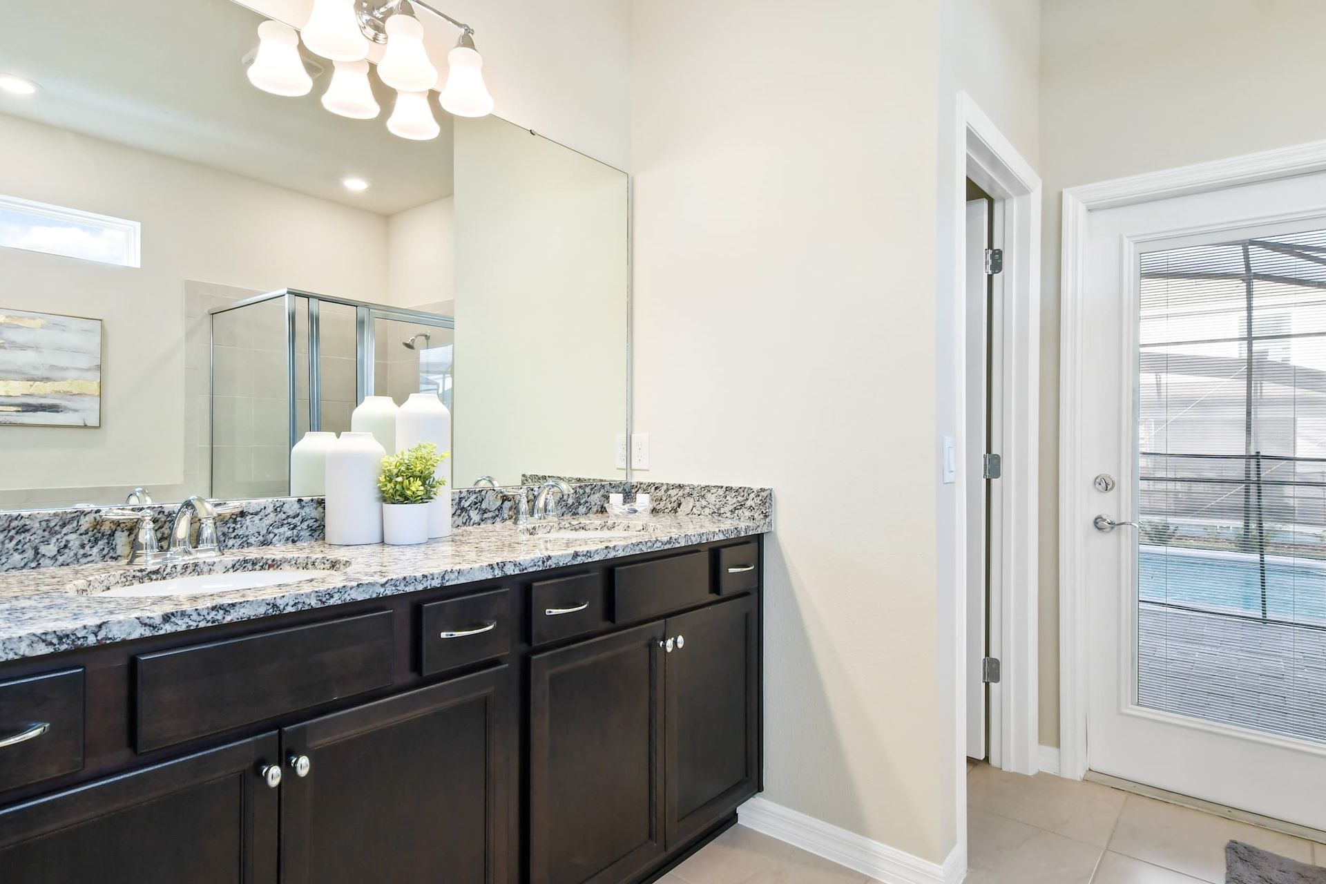 Elegant dual-sink bathroom with granite counters and direct access to the pool.