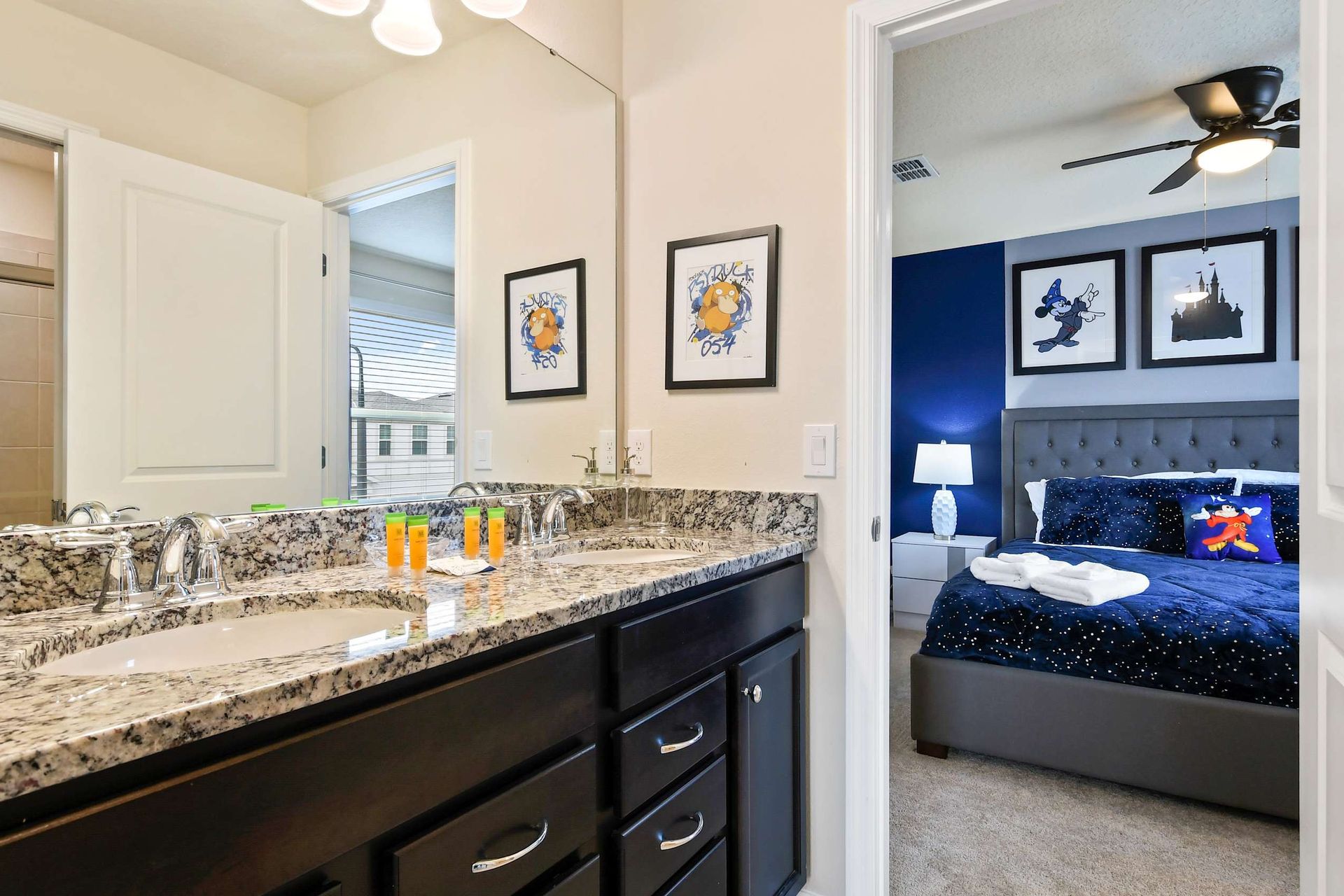 Granite double vanity bathroom with walk-in shower and whimsical themed bedroom view.