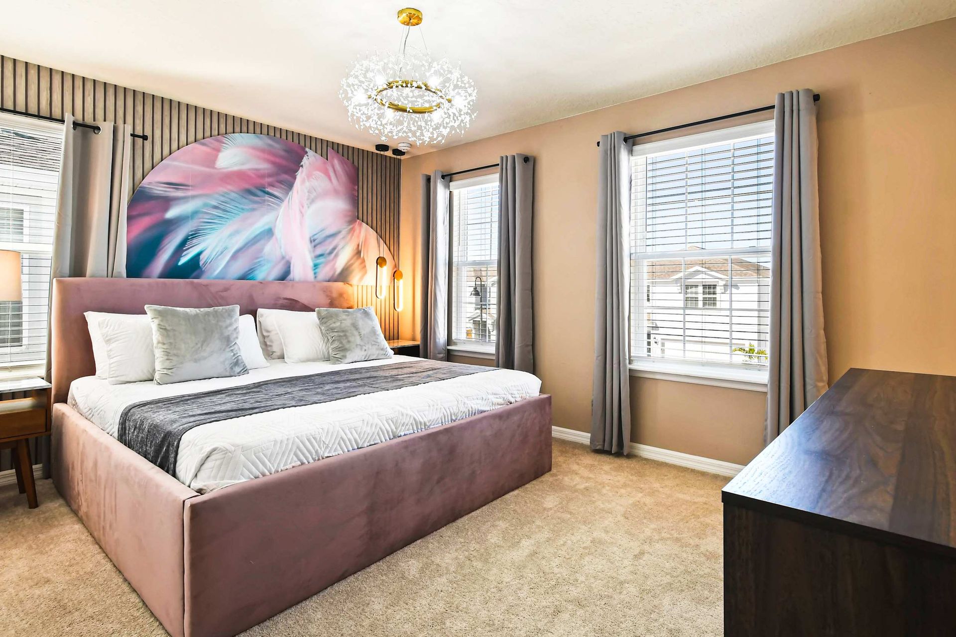 Elegant bedroom with soft pastel accents, velvet bed, and a sparkling chandelier.