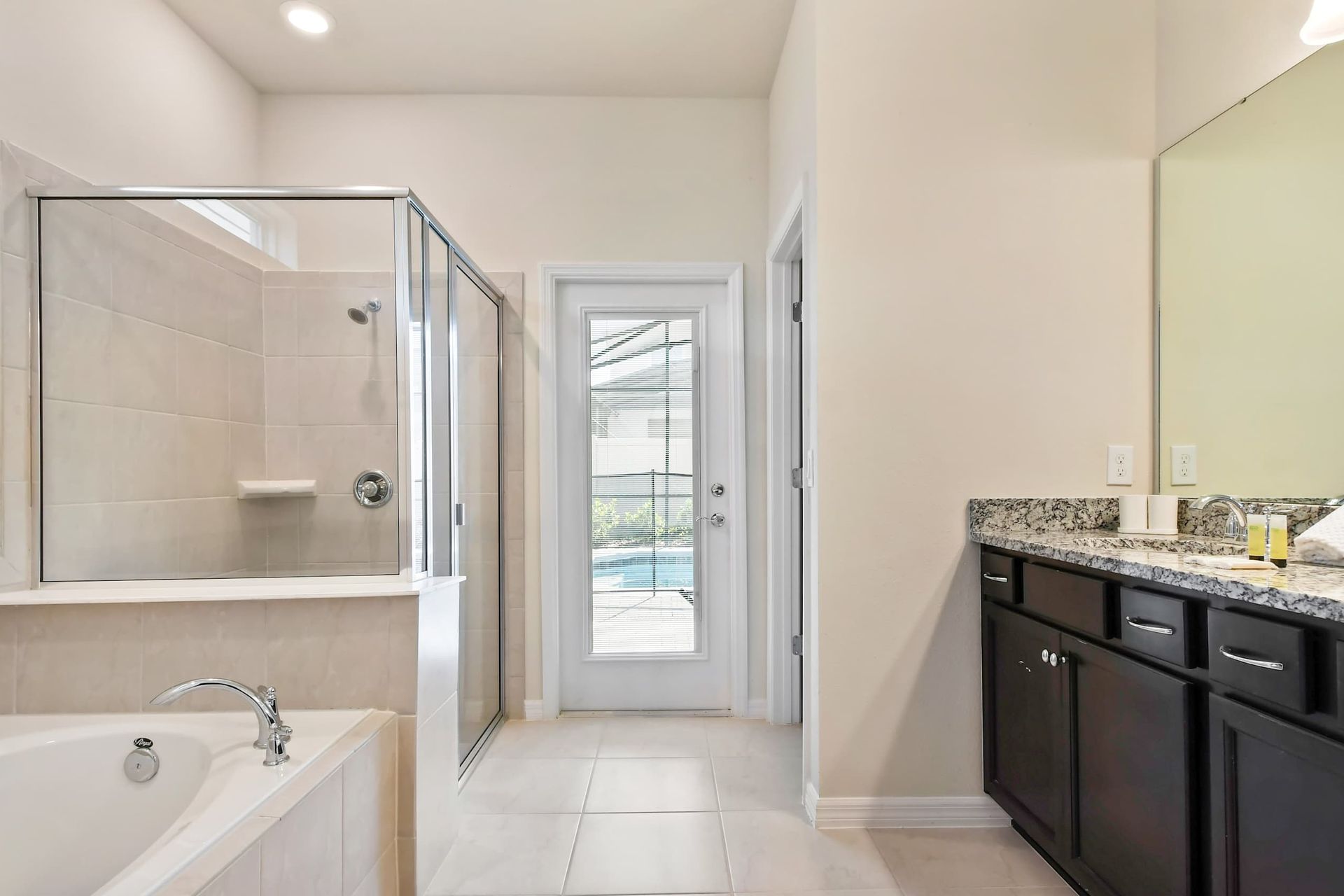 Luxurious bathroom with soaking tub, glass shower, and poolside access.