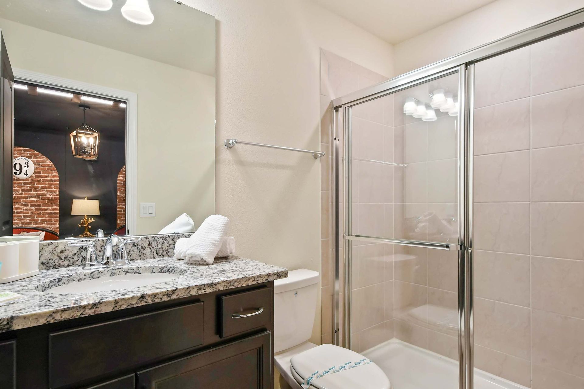 Modern bathroom with granite countertop, glass shower, and fresh amenities.