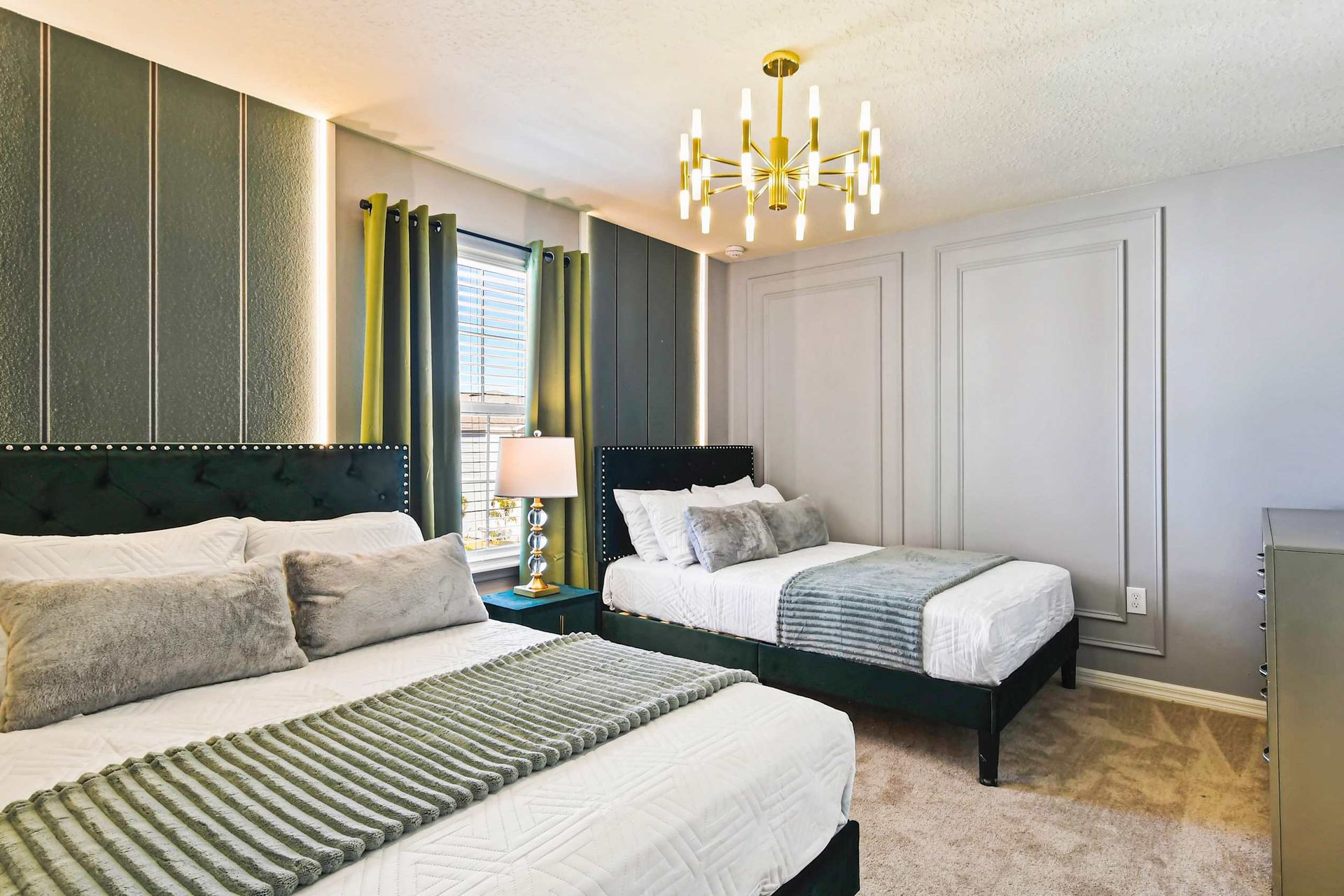 Sophisticated bedroom with double beds, plush accents, and a gold chandelier.