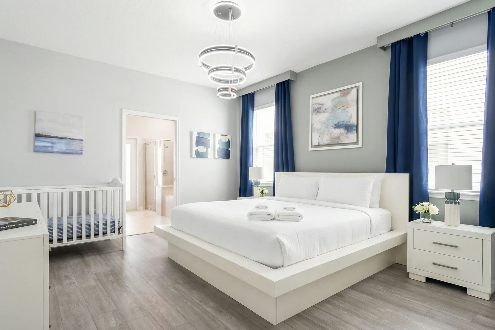 Spacious modern suite with king bed, crib, ensuite bath, and calming decor.