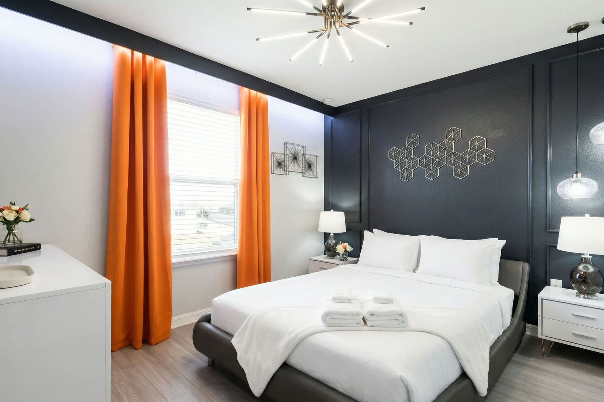 Modern room with bold black accents, striking orange curtains, and sleek lighting.