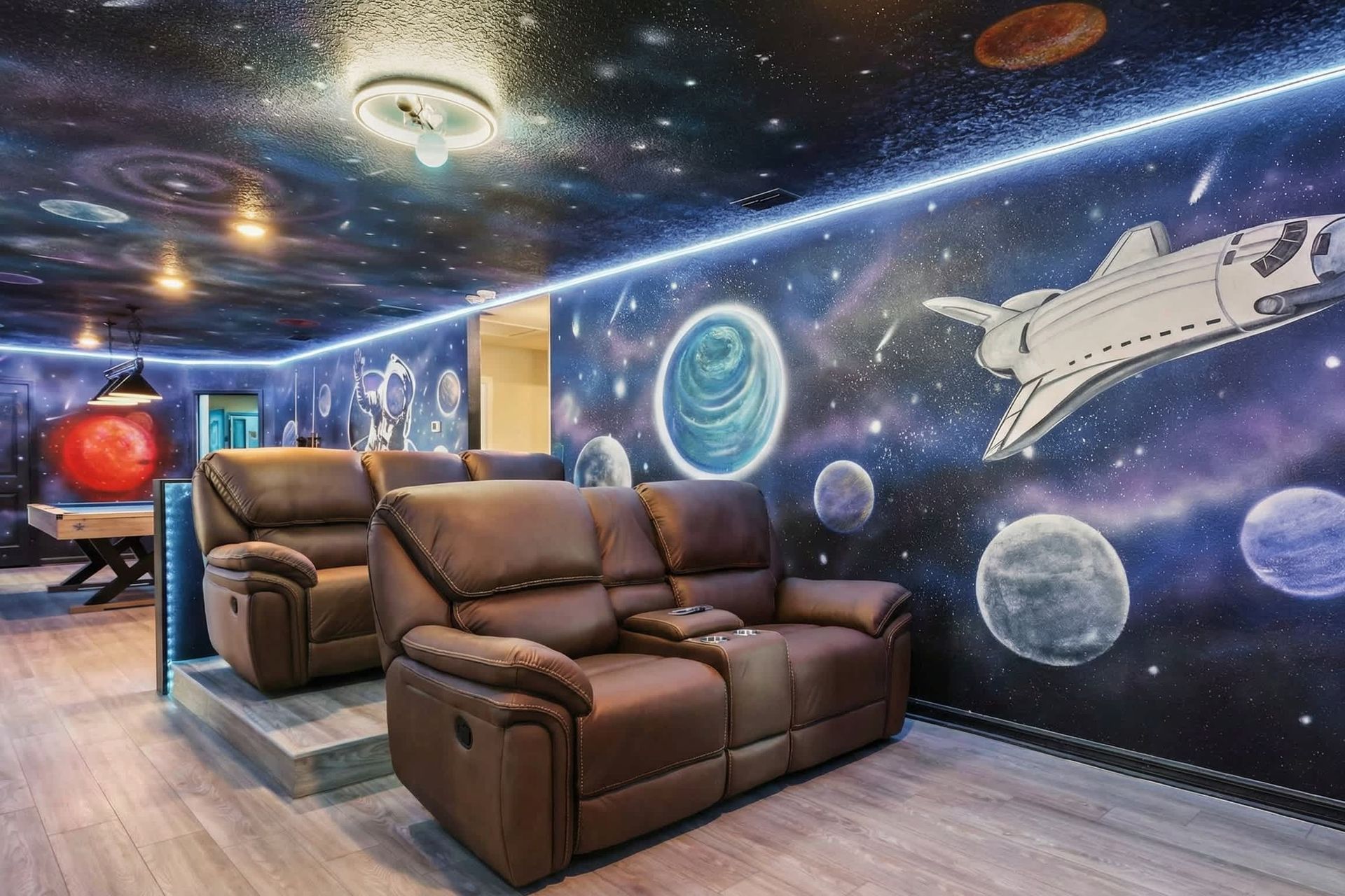 Out-of-this-world theater room with galaxy murals, glowing lights, and plush seating.