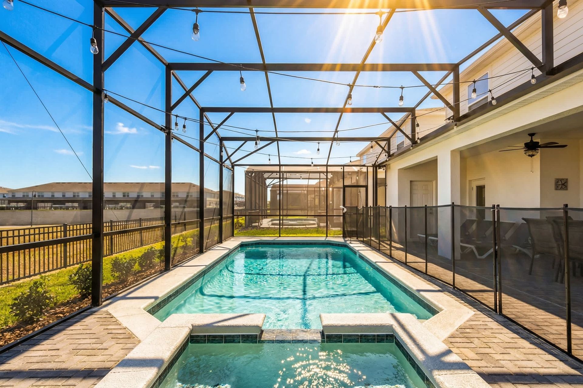 Private screened pool and spa with lounge seating, string lights, and sunny vibes.