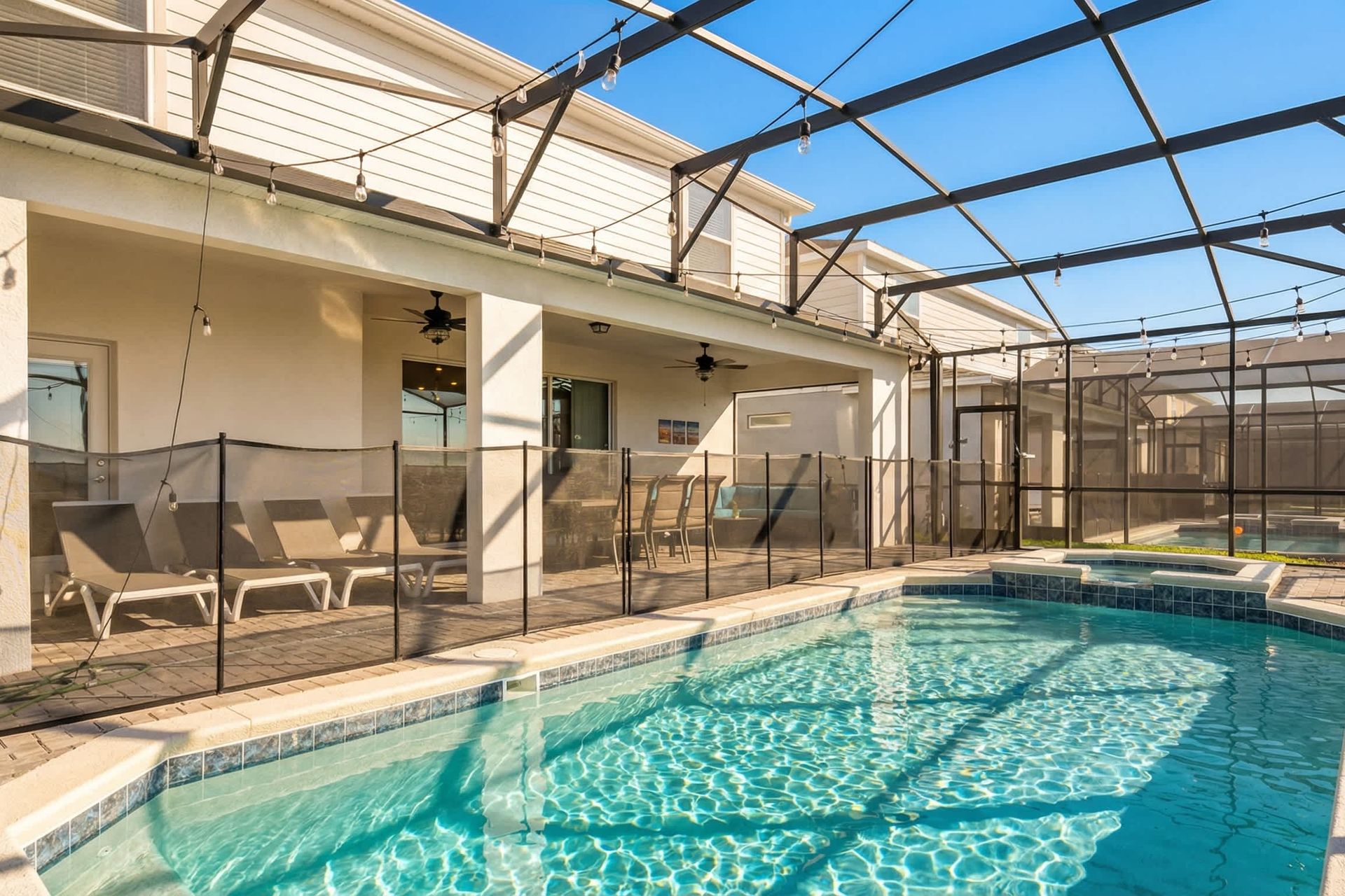Spacious screened pool and spa with loungers, dining area, and cozy covered patio.