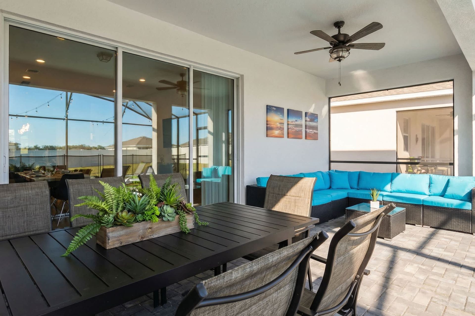 Chic covered patio with dining table, lounge chairs, and a bright turquoise sofa.