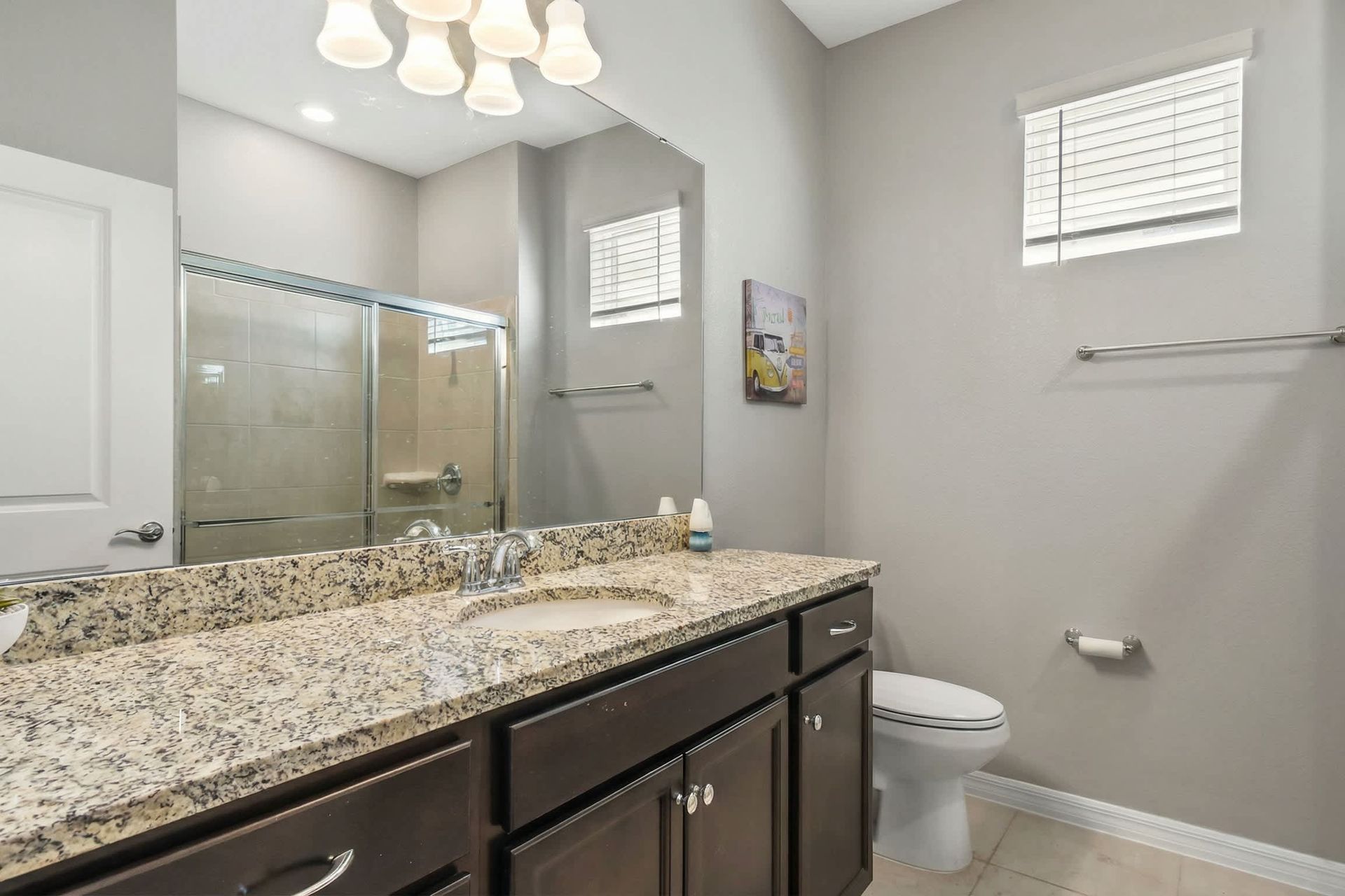 Modern full bath with granite vanity and glass-enclosed walk-in shower.