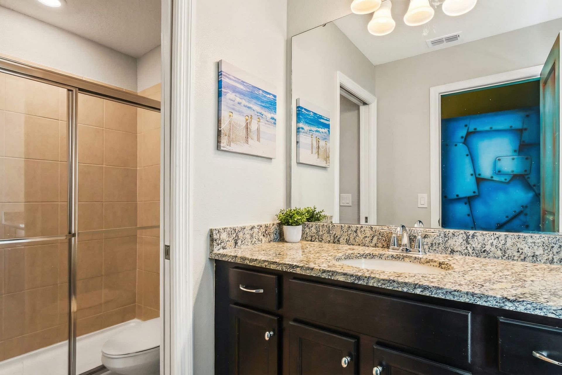 Stylish bathroom with granite countertop and a sleek glass-door walk-in shower.