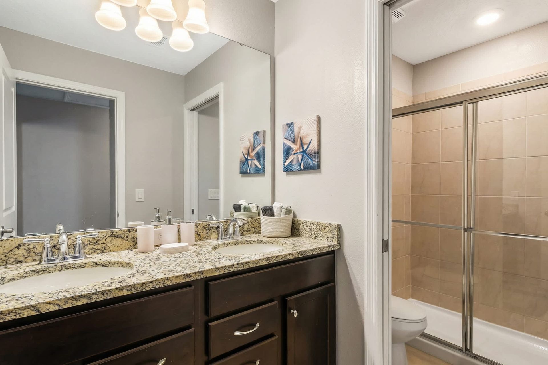Modern bathroom with double sinks, granite counters, and a spacious glass shower.