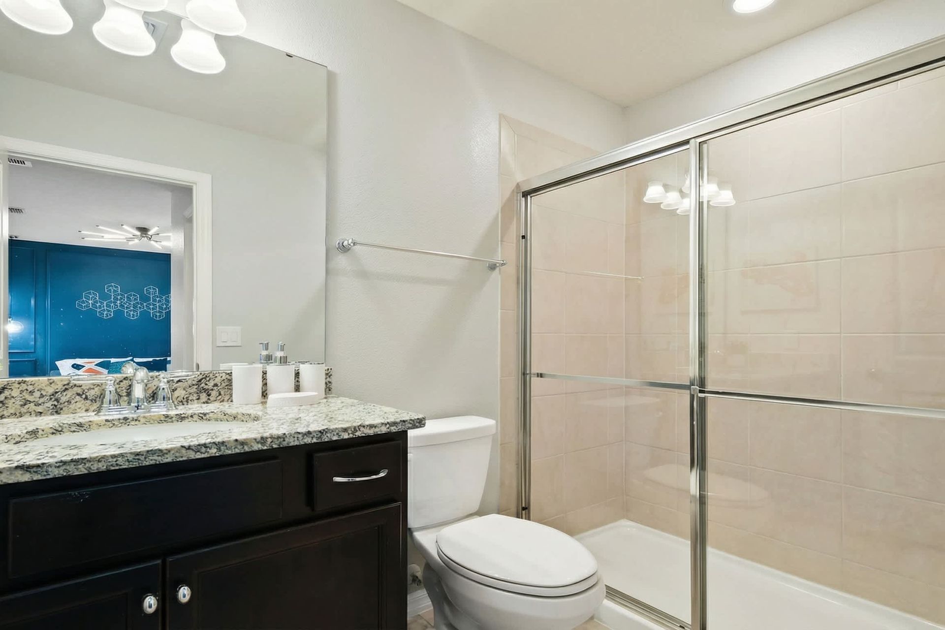 Modern bathroom with granite countertops and sleek glass-enclosed shower.