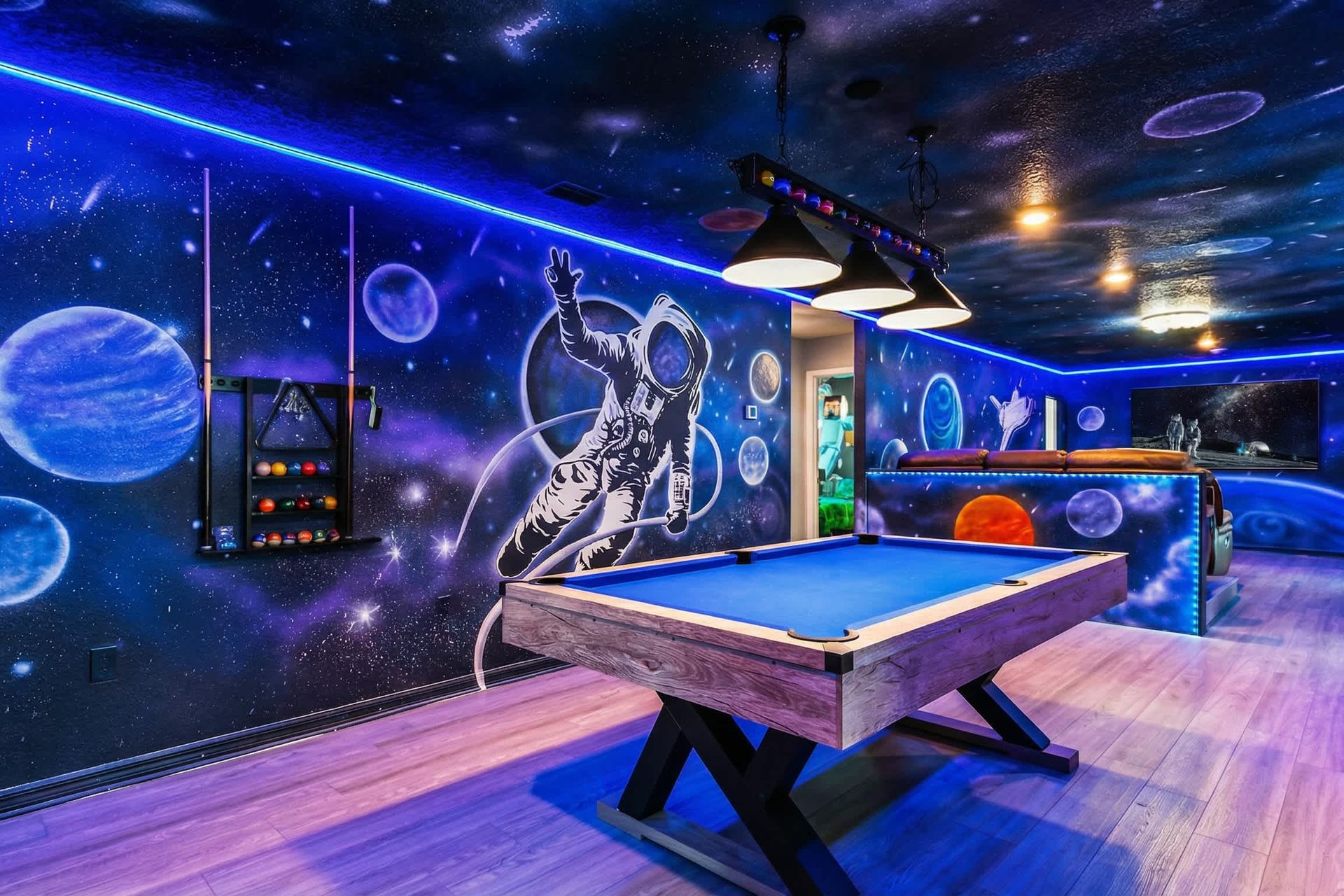 Stunning space-themed game room with billiards, neon lights, and cosmic wall art.