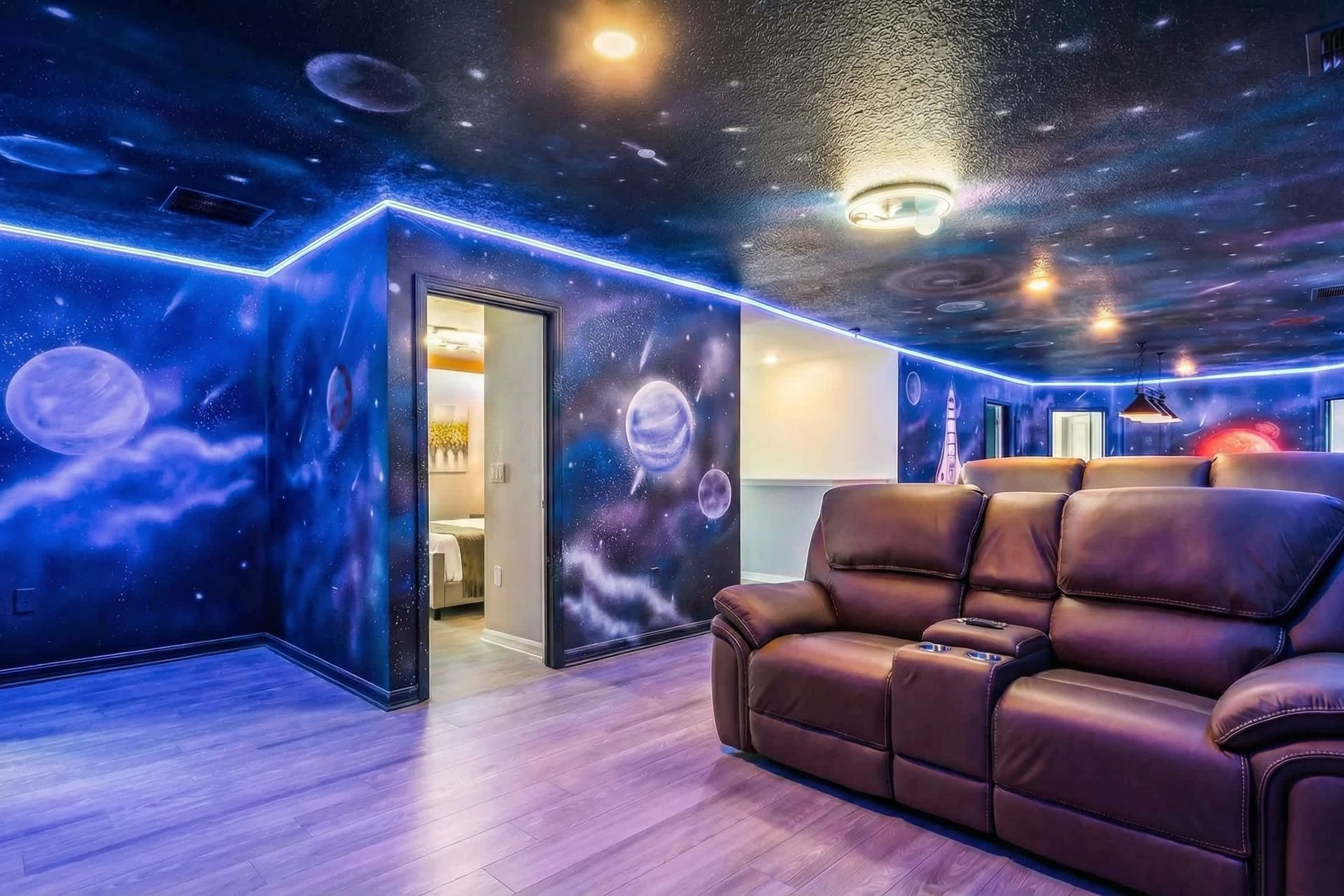 Immersive galaxy-themed theater with LED glow, starry walls, and luxe recliners.