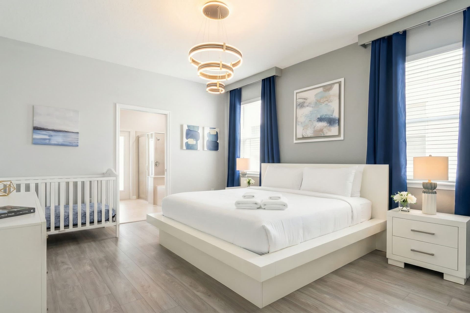 Spacious modern suite with king bed, crib, ensuite bath, and calming decor.
