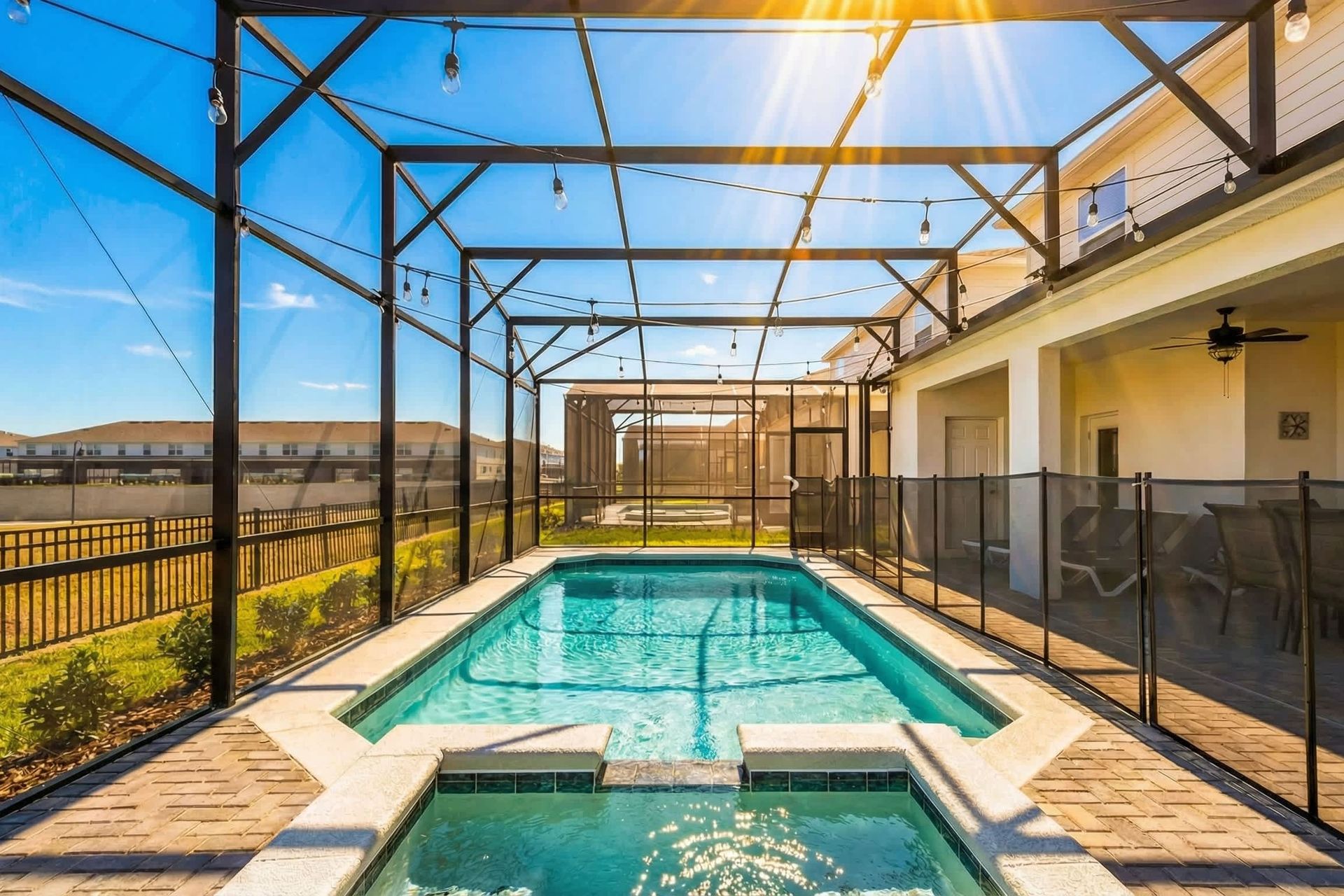 Private screened pool and spa with lounge seating, string lights, and sunny vibes.