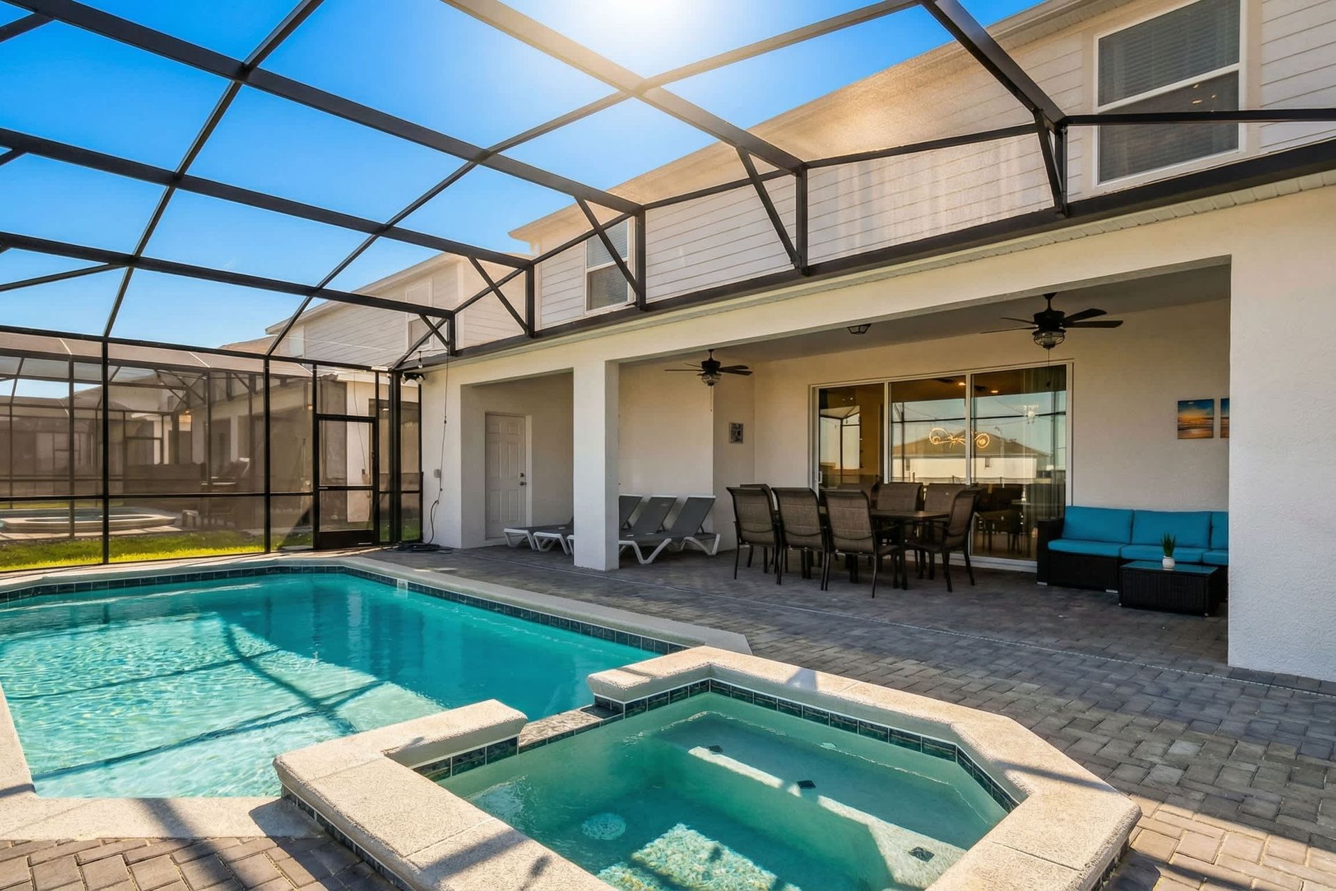 Screened-in pool and spa with lounge seating, dining area, and relaxing outdoor vibes.