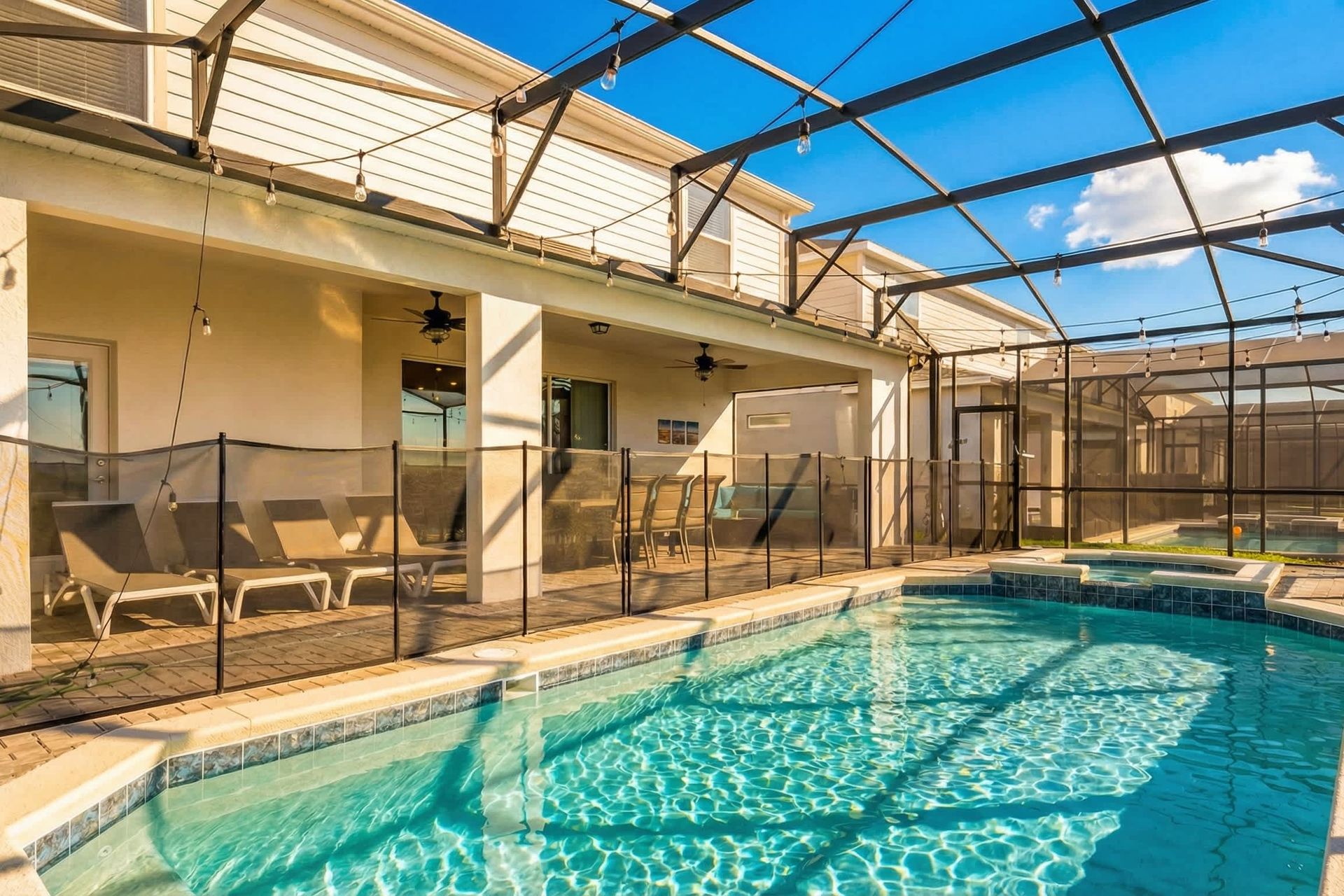 Spacious screened pool and spa with loungers, dining area, and cozy covered patio.