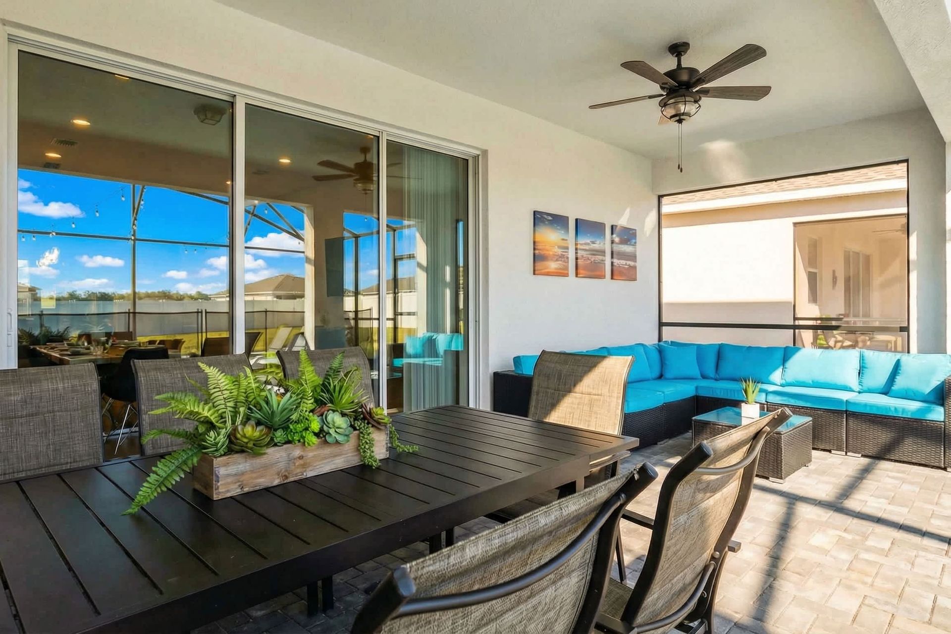 Chic covered patio with dining table, lounge chairs, and a bright turquoise sofa.
