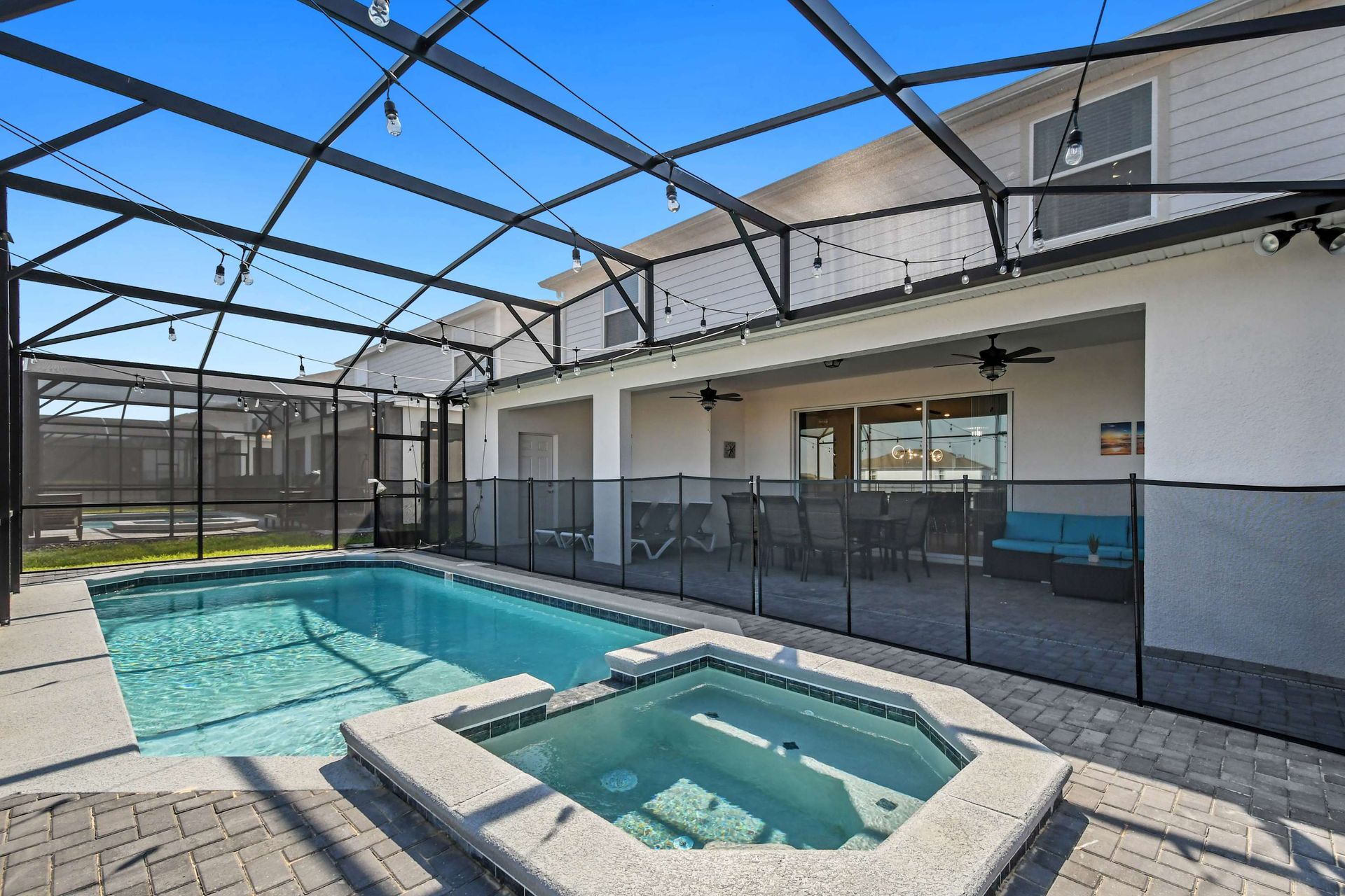 Screened-in pool and spa with lounge seating, dining area, and relaxing outdoor vibes.