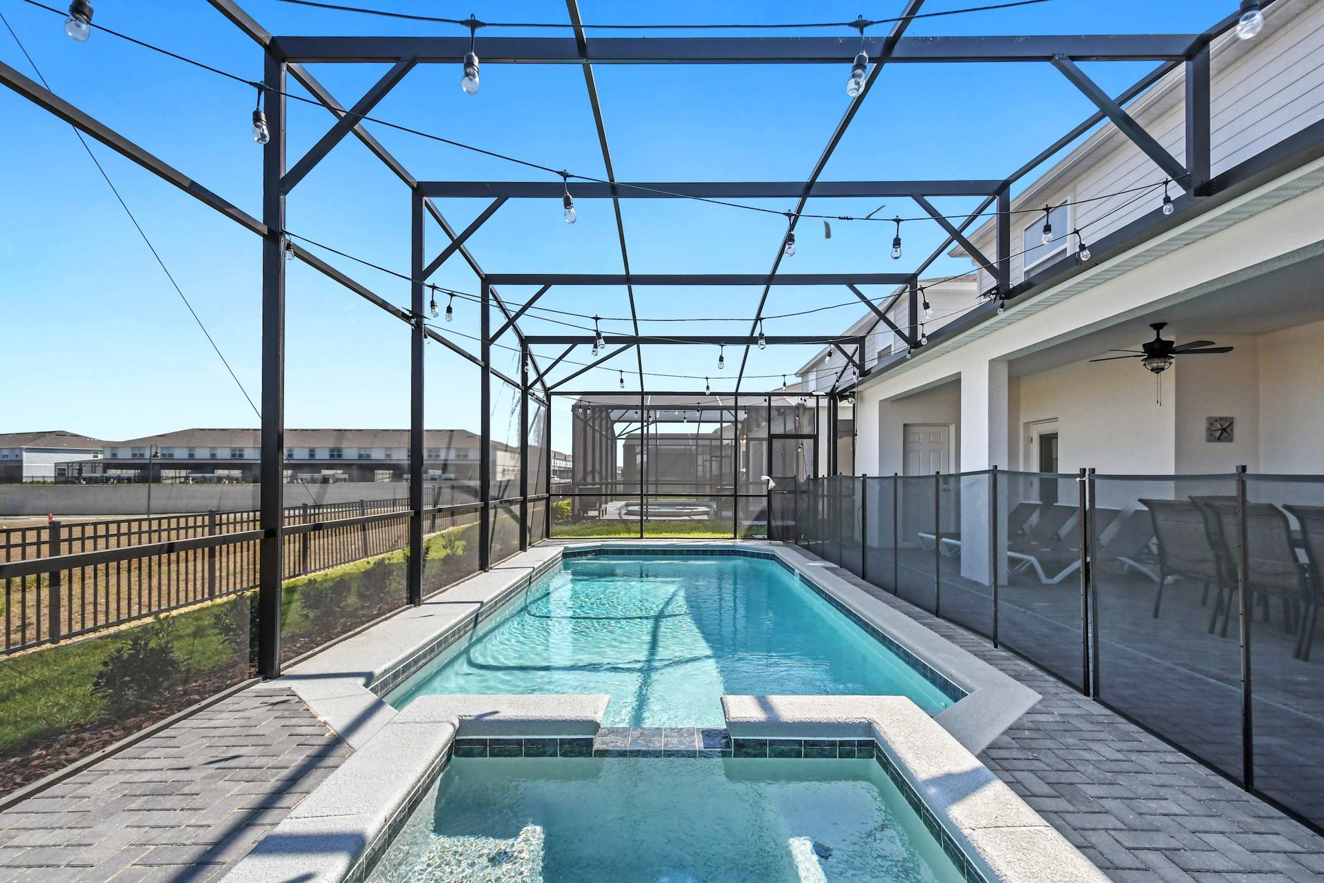 Private screened pool and spa with lounge seating, string lights, and sunny vibes.