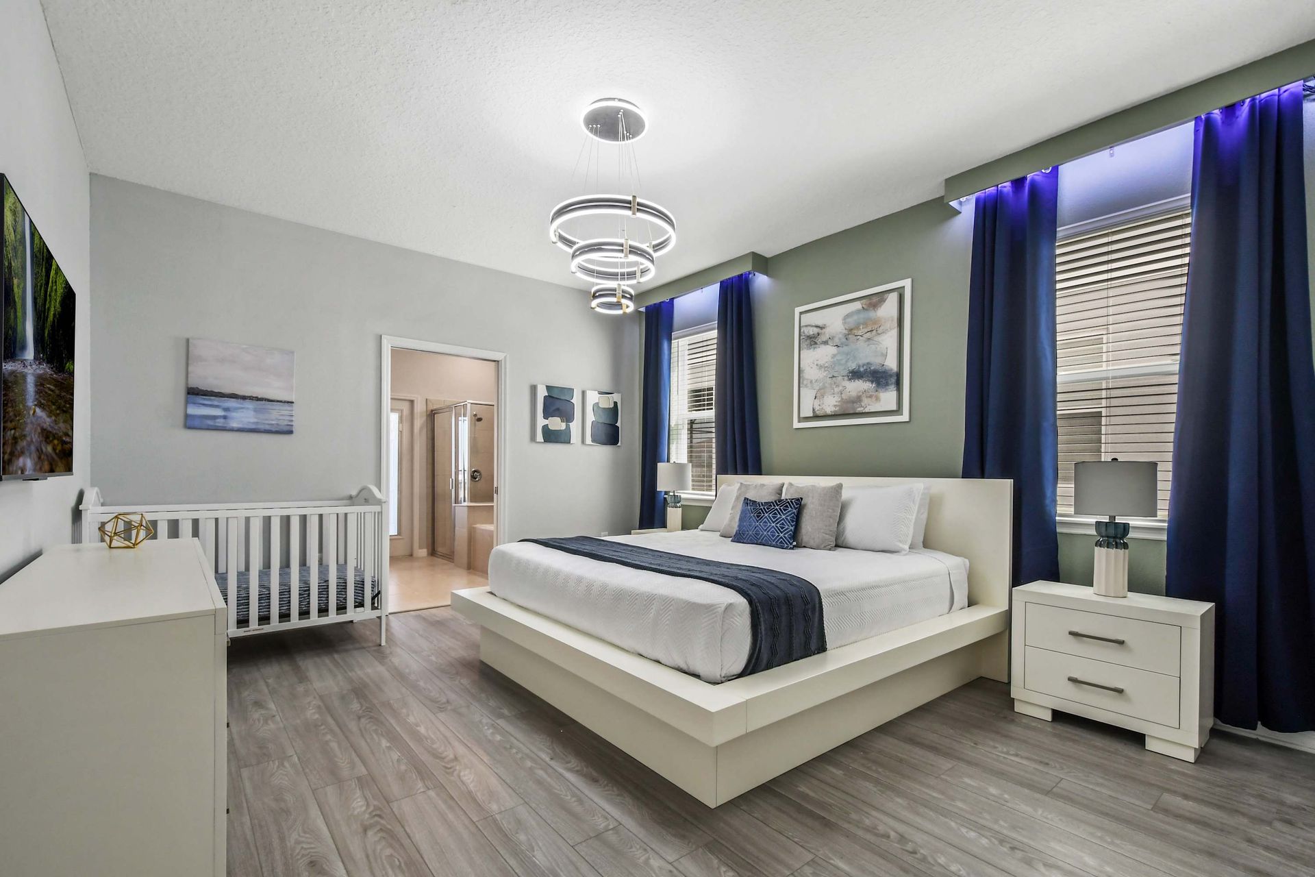 Spacious modern suite with king bed, crib, ensuite bath, and calming decor.