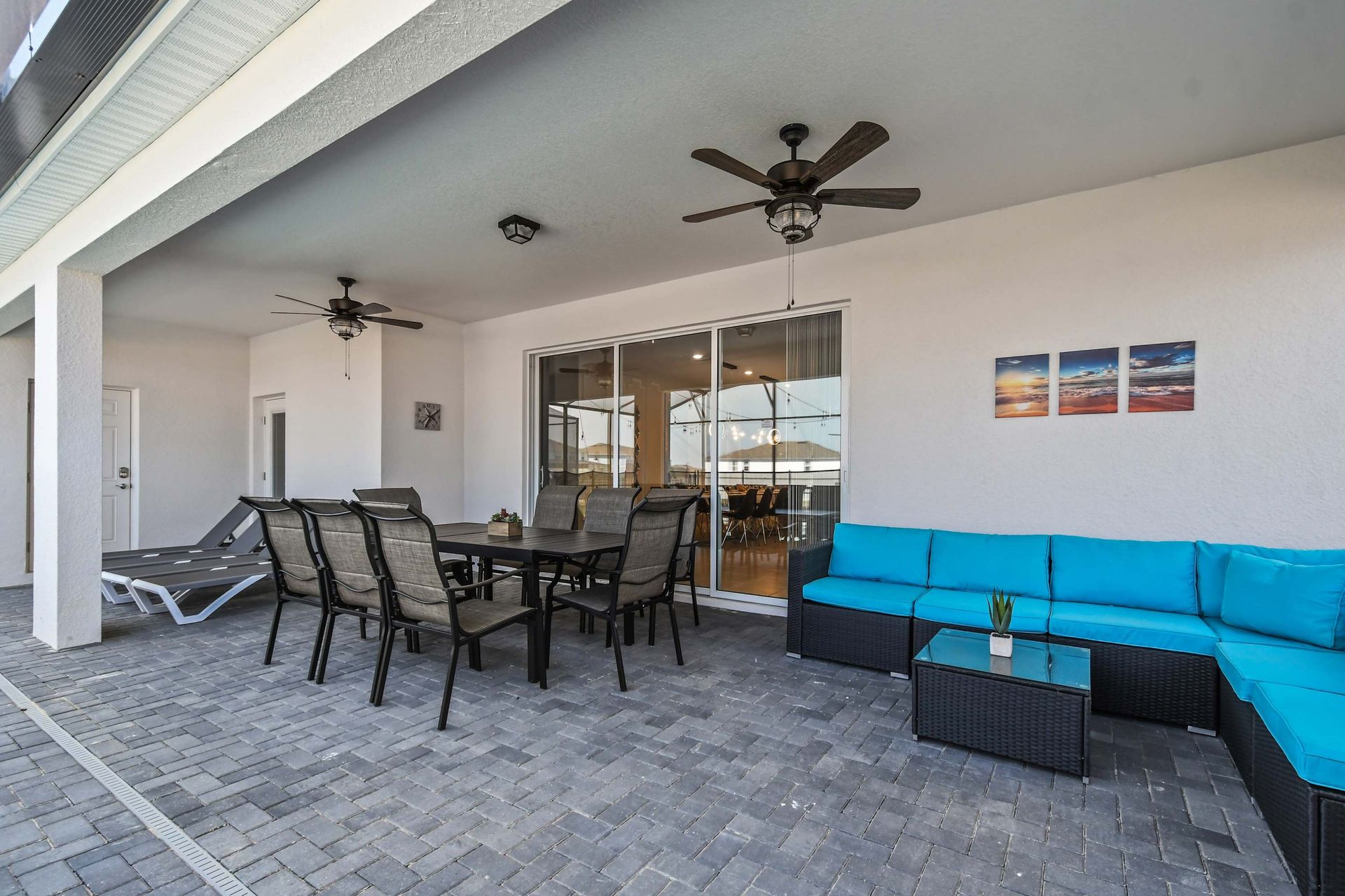 Chic covered patio with dining table, lounge chairs, and a bright turquoise sofa.