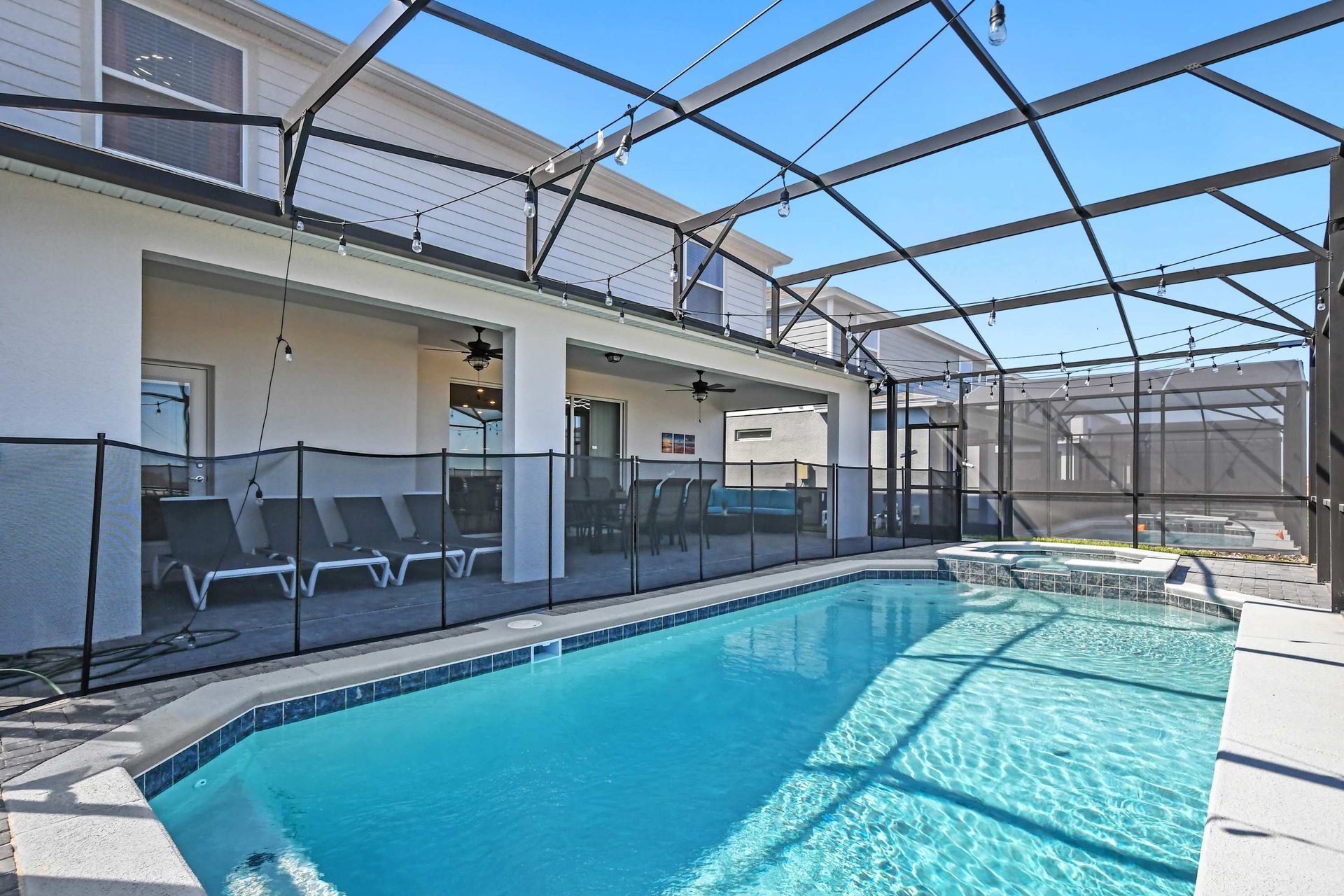 Spacious screened pool and spa with loungers, dining area, and cozy covered patio.