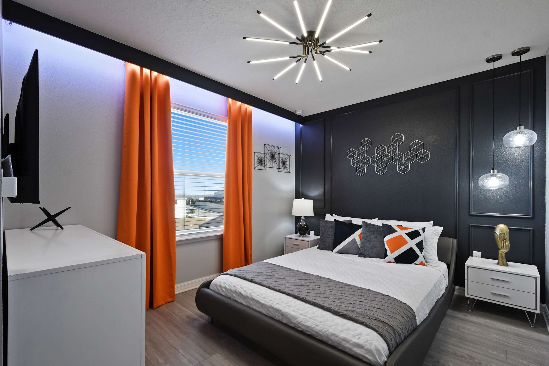 Modern room with bold black accents, striking orange curtains, and sleek lighting.