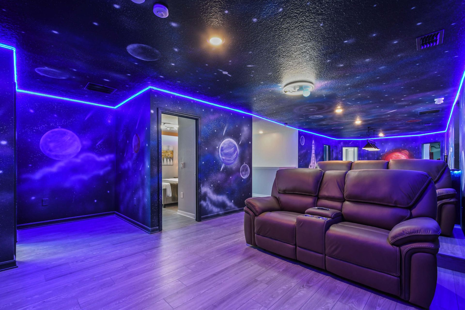 Immersive galaxy-themed theater with LED glow, starry walls, and luxe recliners.
