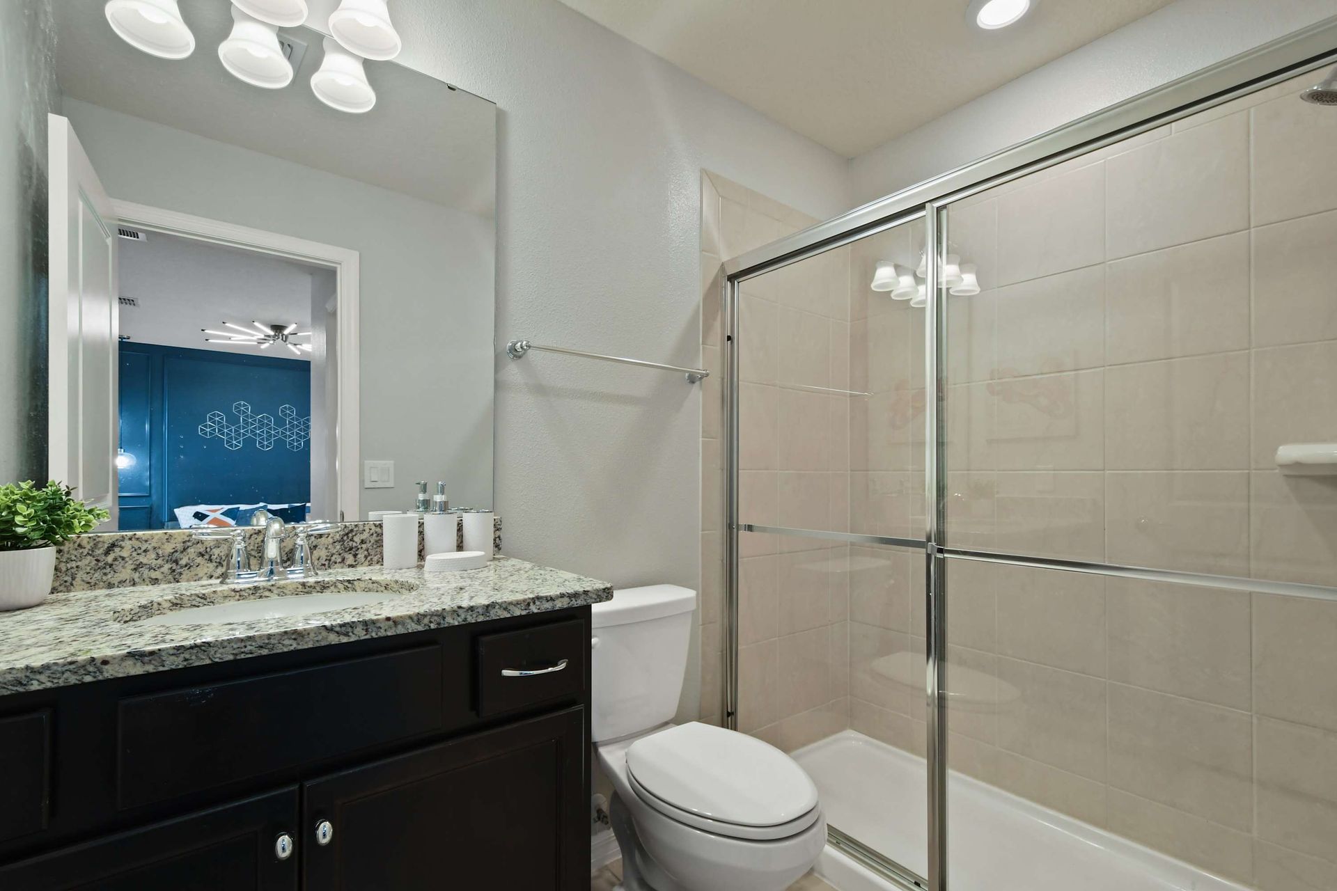 Modern bathroom with granite countertops and sleek glass-enclosed shower.