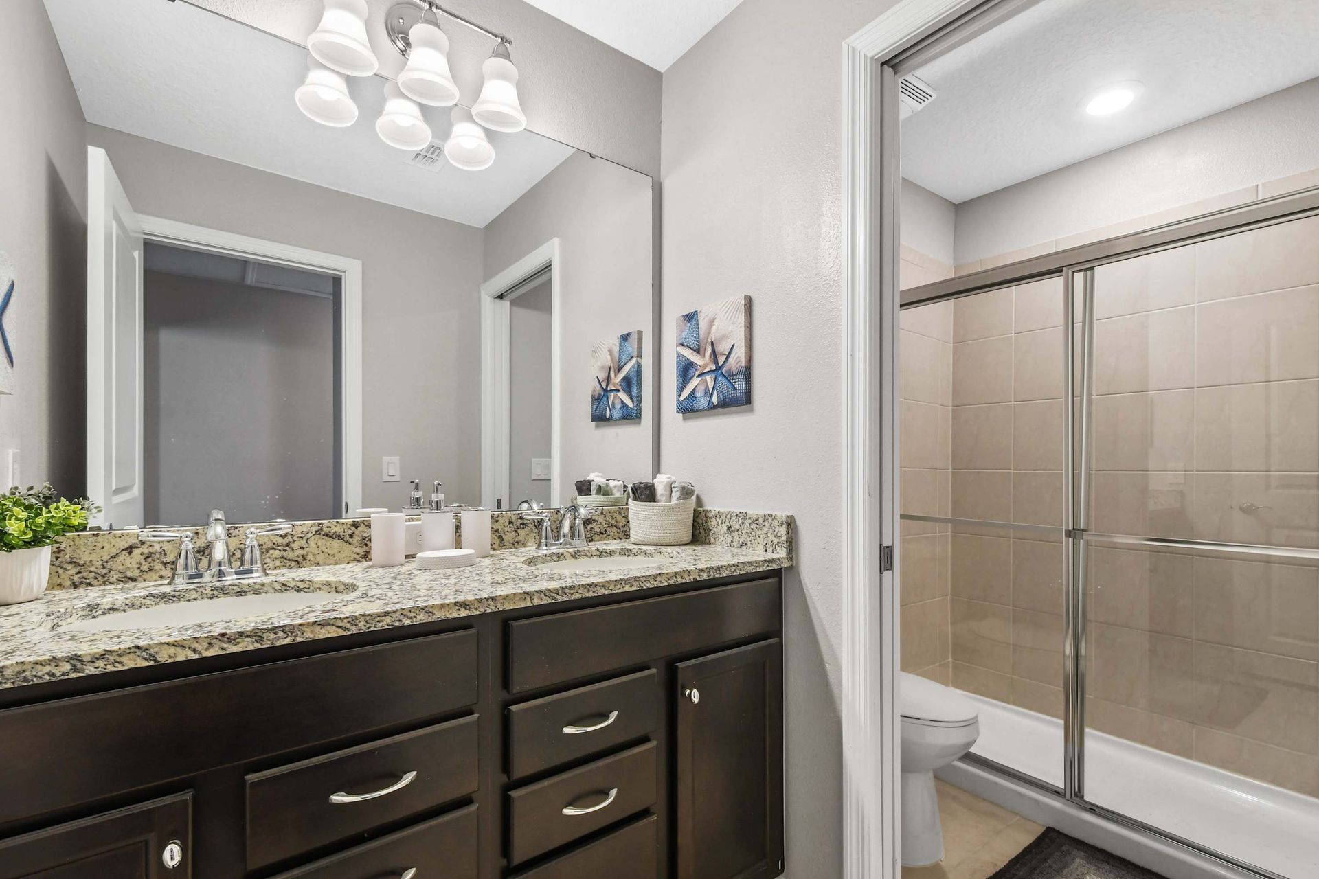 Modern bathroom with double sinks, granite counters, and a spacious glass shower.