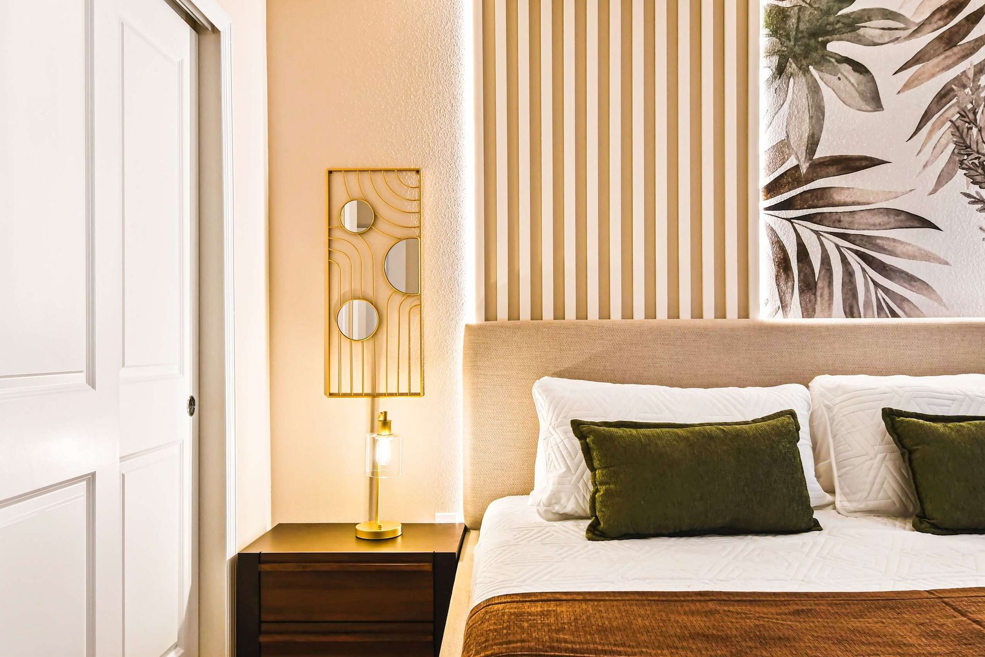 Modern bedroom with earthy tones, gold accents, and cozy lighting for a relaxing stay.