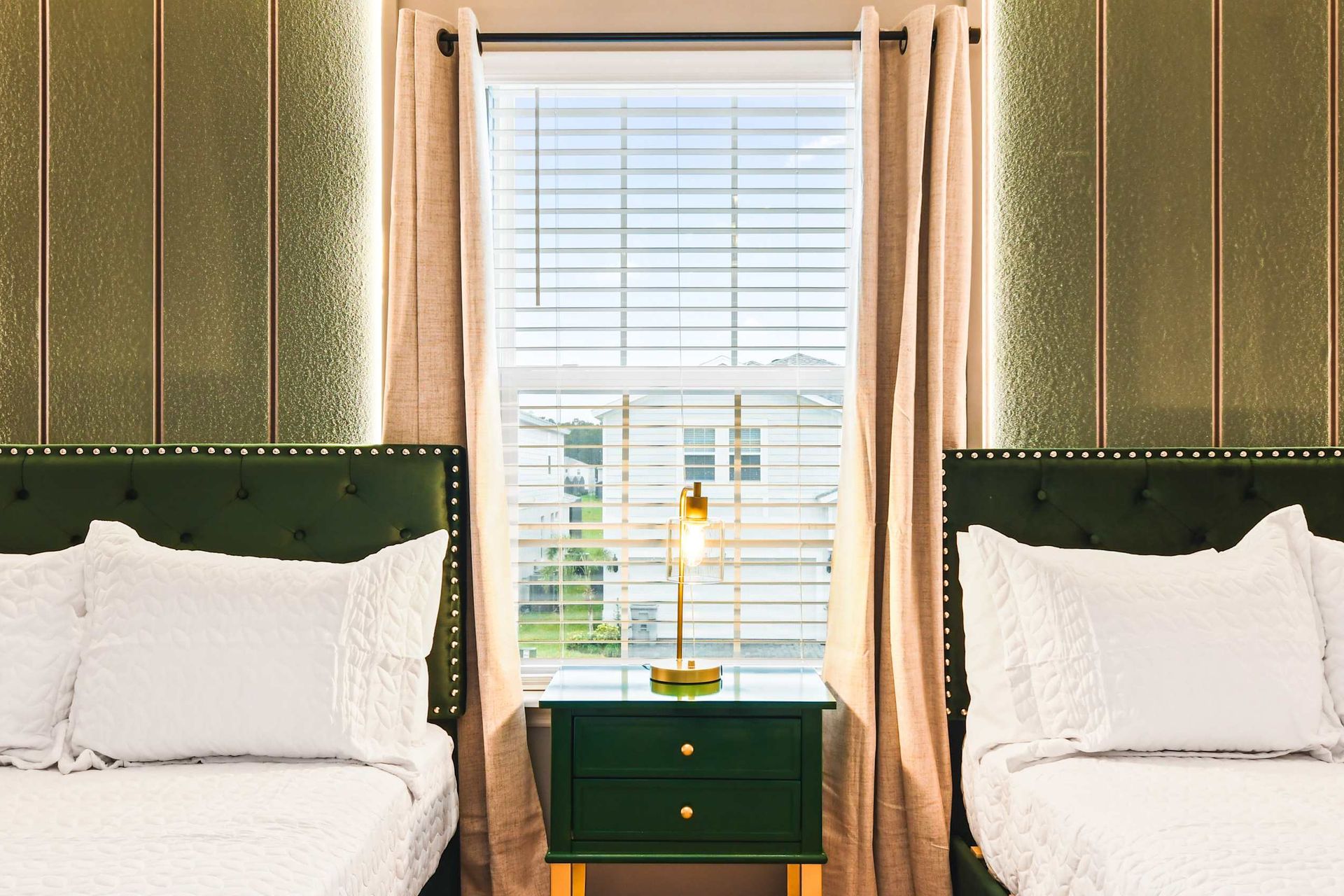 Elegant bedroom with twin beds, gold accents, and soft lighting for a cozy stay.