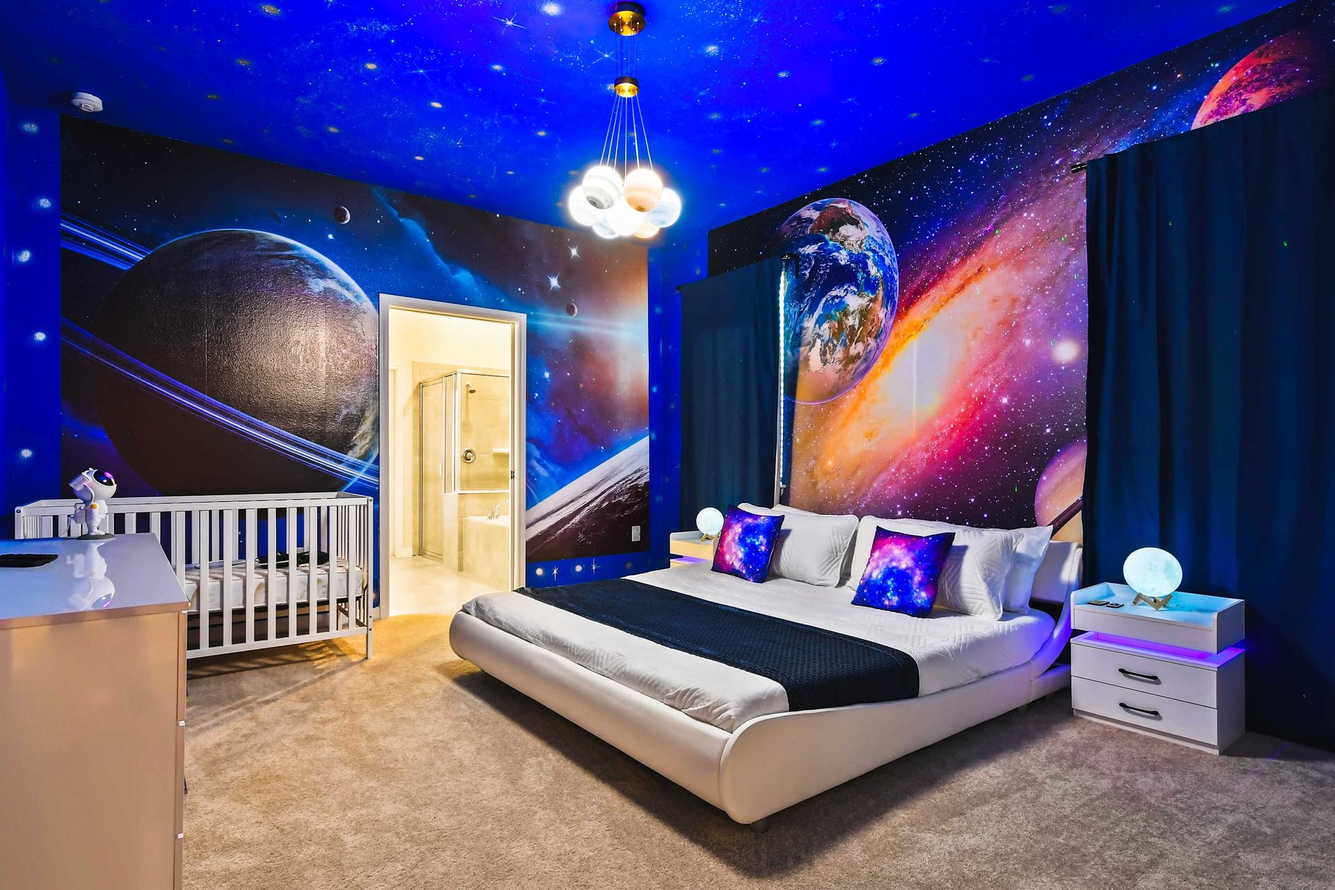 Experience the vastness of the universe in this space-themed bedroom. Complete with cosmic wall murals of planets and stars, the room included a modern bed.