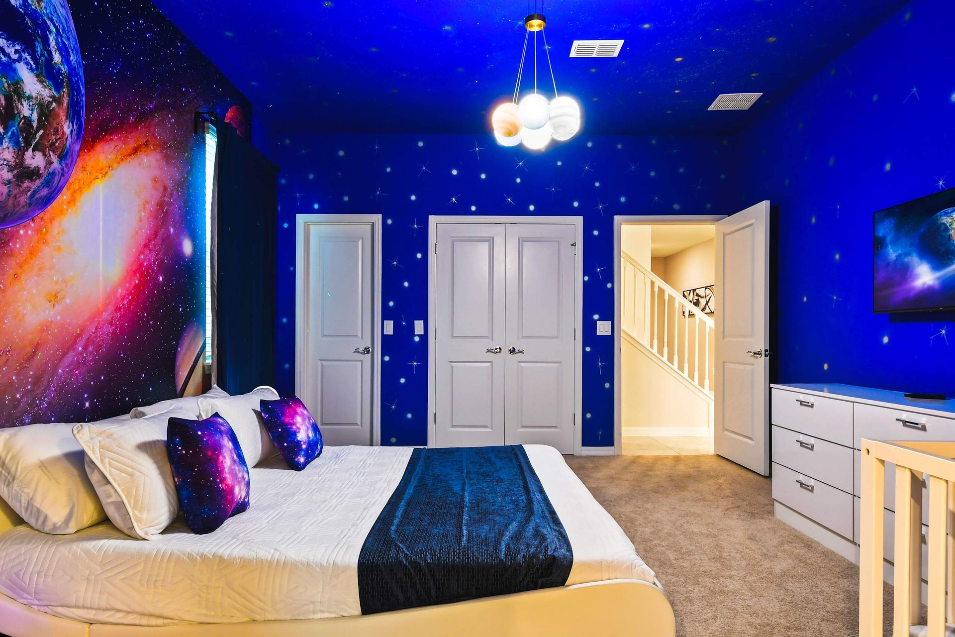 Space-themed bedroom with galaxy murals and cozy decor for an out-of-this-world stay.