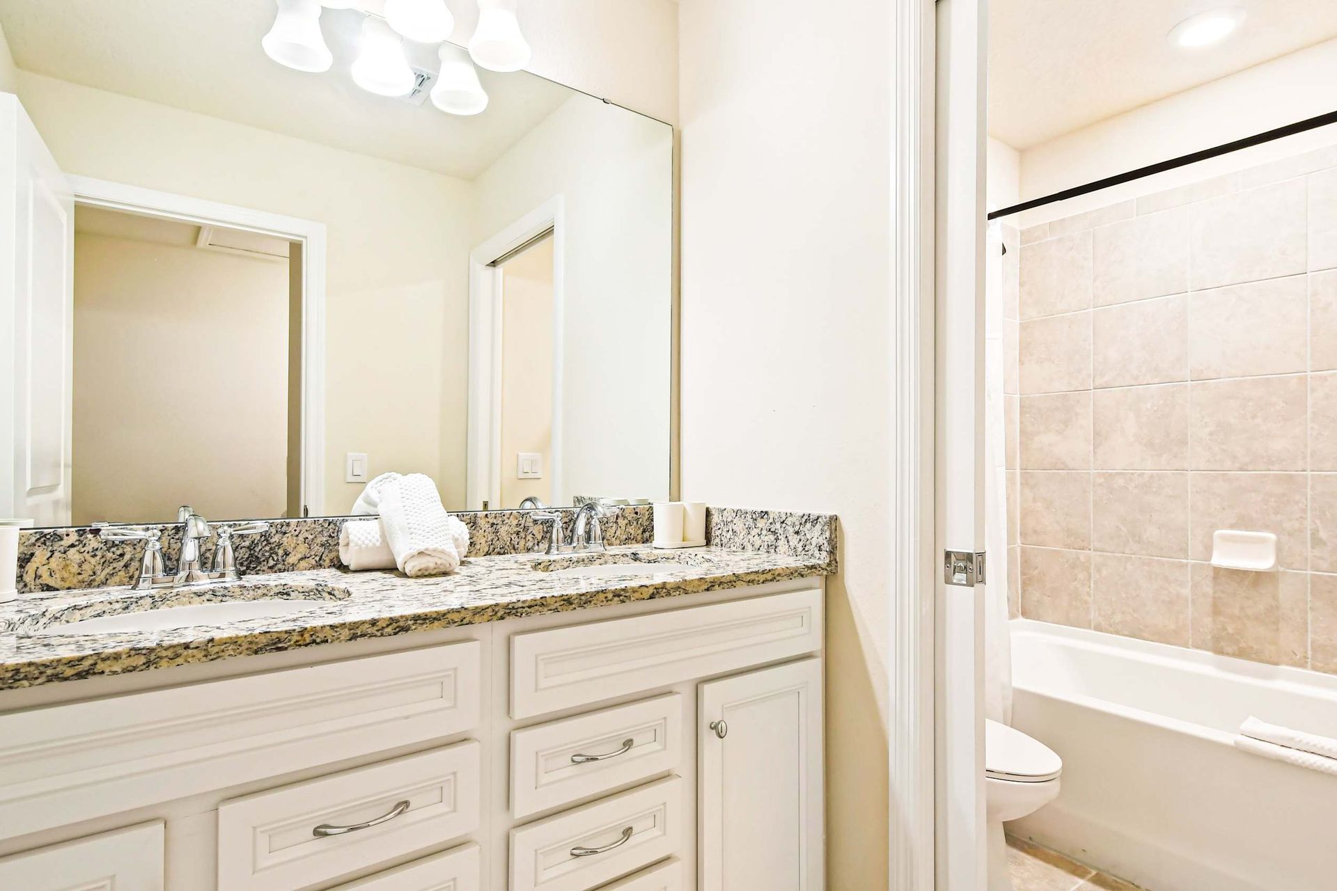 Modern bathroom with granite double vanity, tub shower combo, and elegant decor
