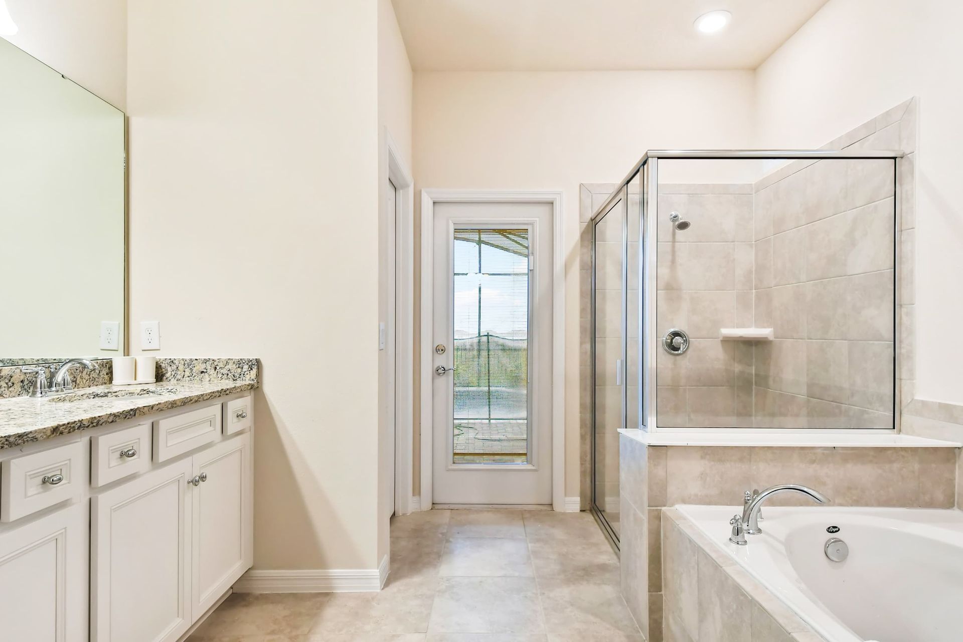 Spacious bathroom with a glass shower, soaking tub, and granite-topped vanity.